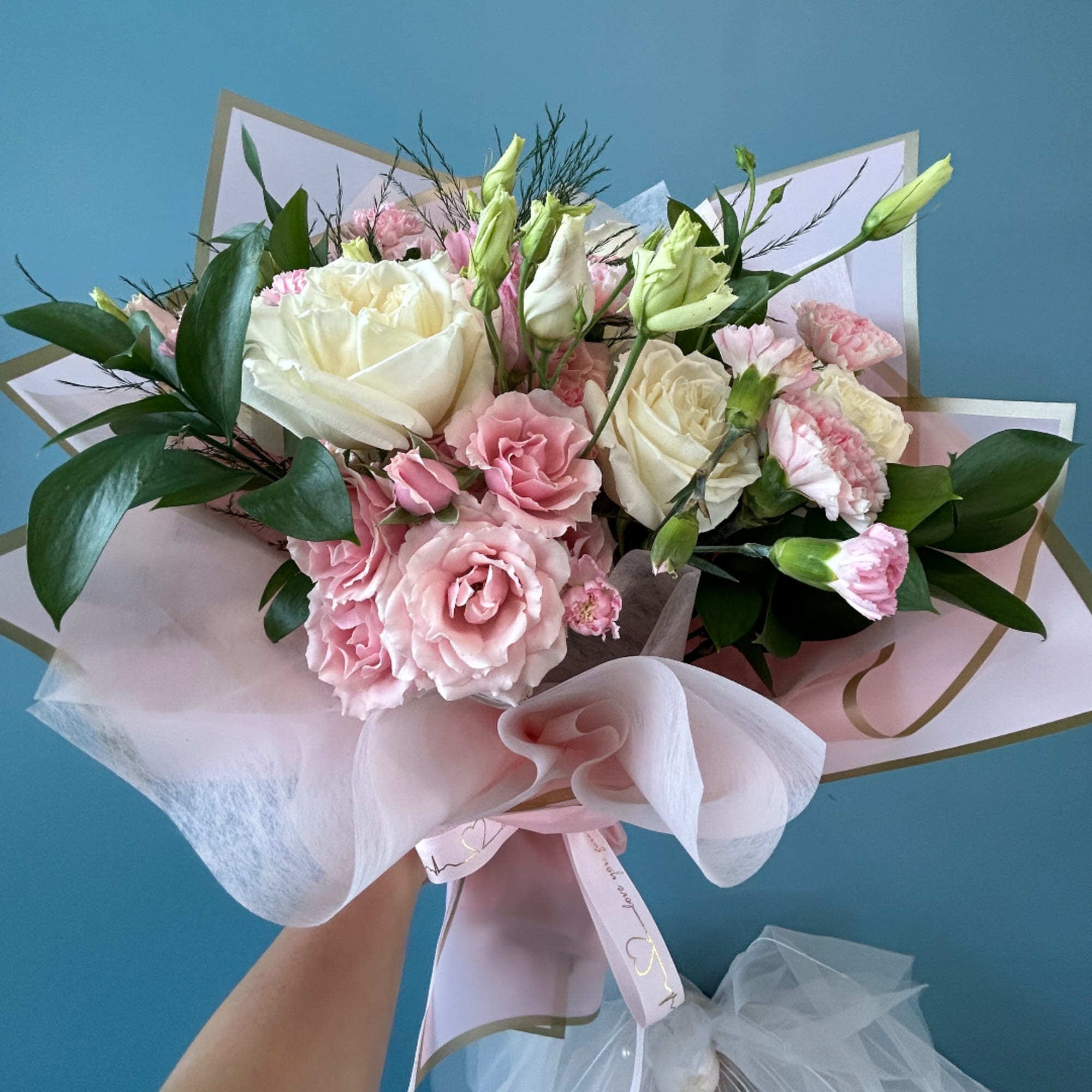 Pink and white bouquet with roses and carnations wrapped in pale paper
