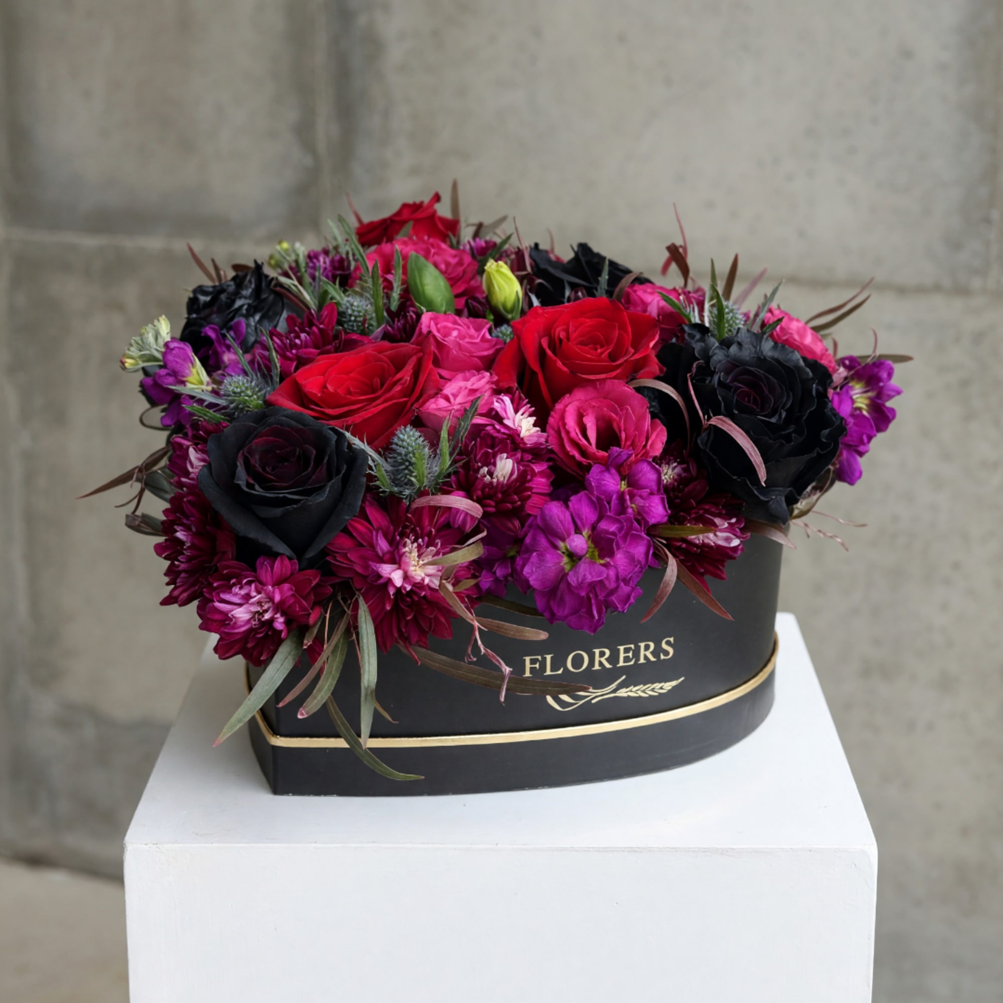 Red, pink, and black roses in a black hat box