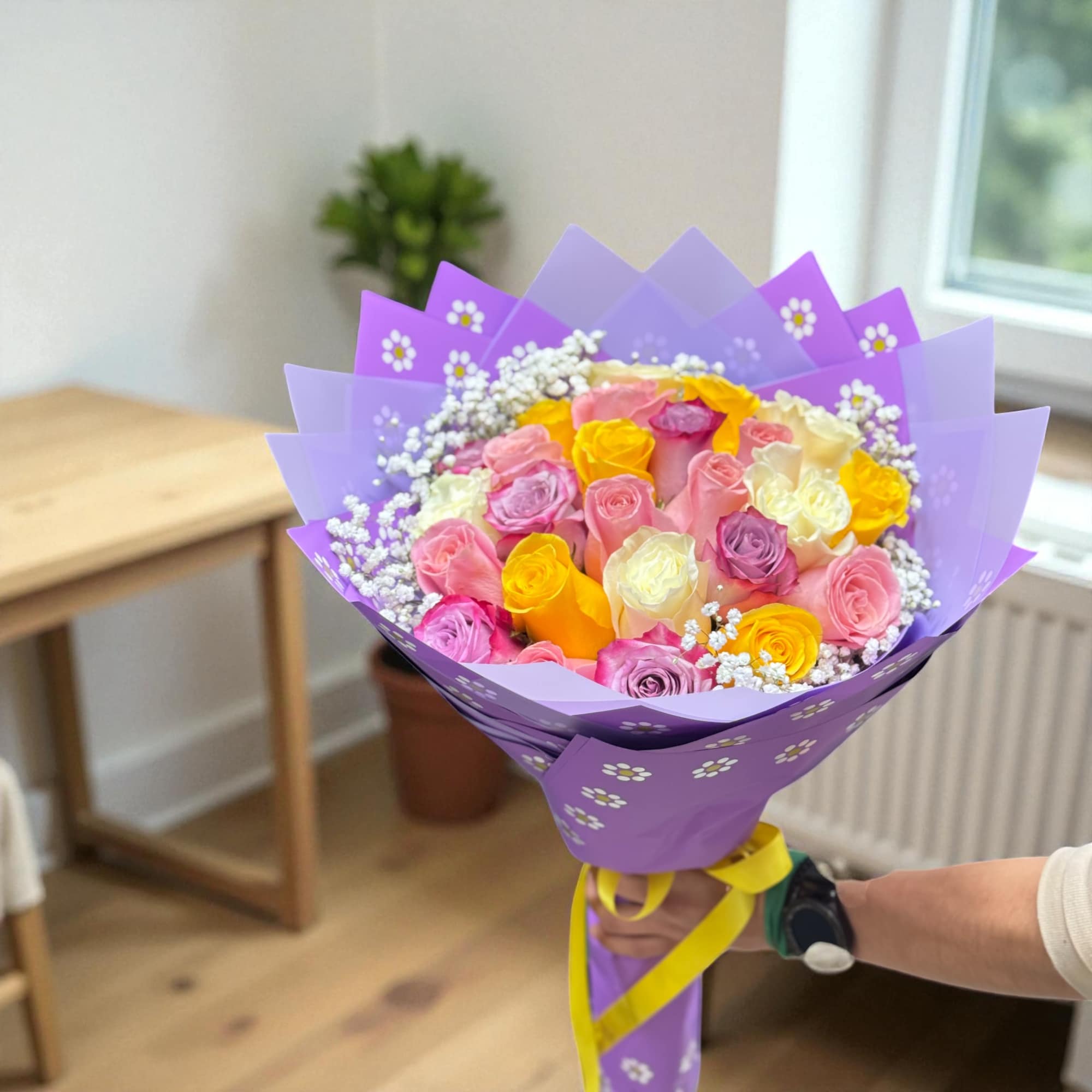 Bouquet of multicolored roses wrapped in purple paper