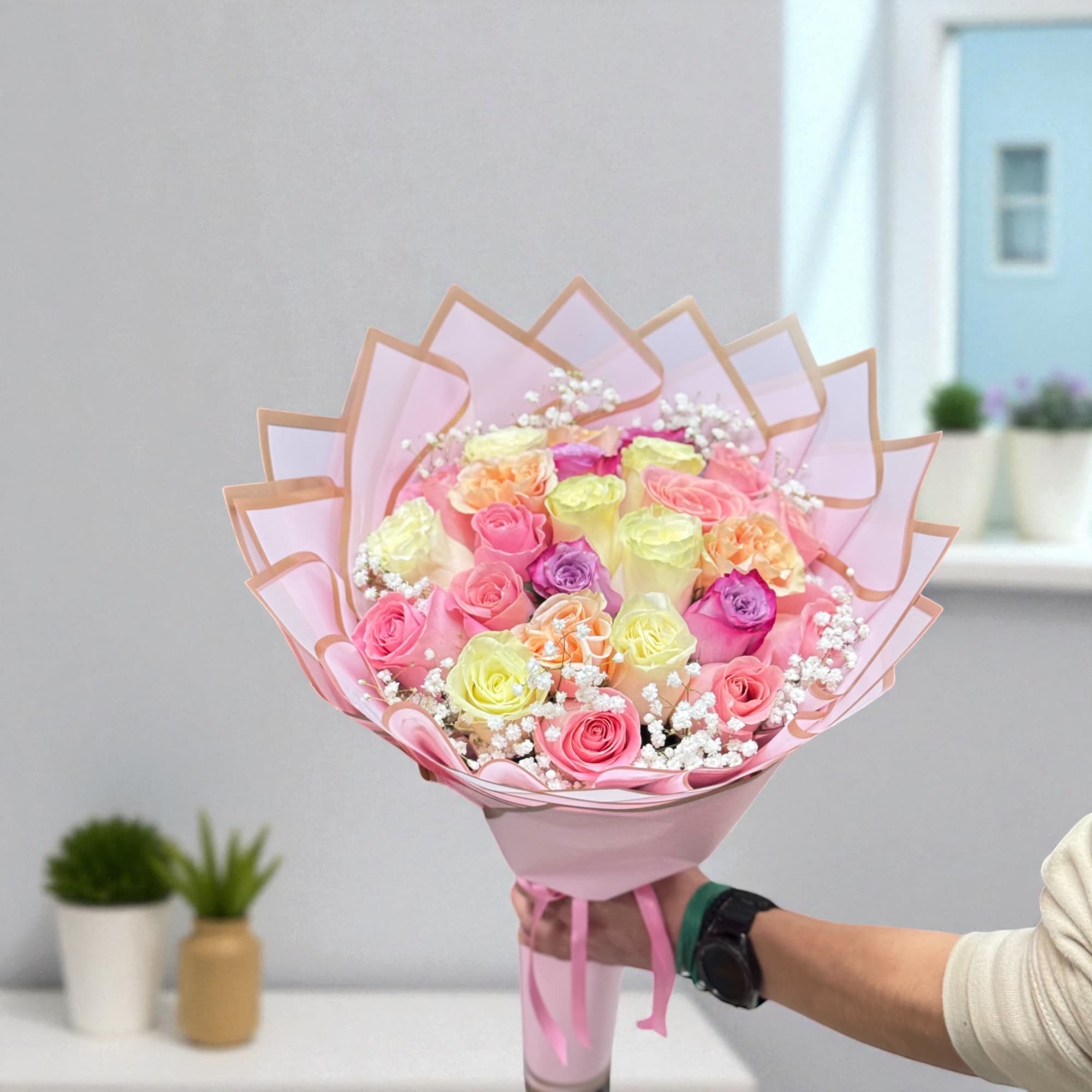 Bouquet of multicolored roses wrapped in pink paper