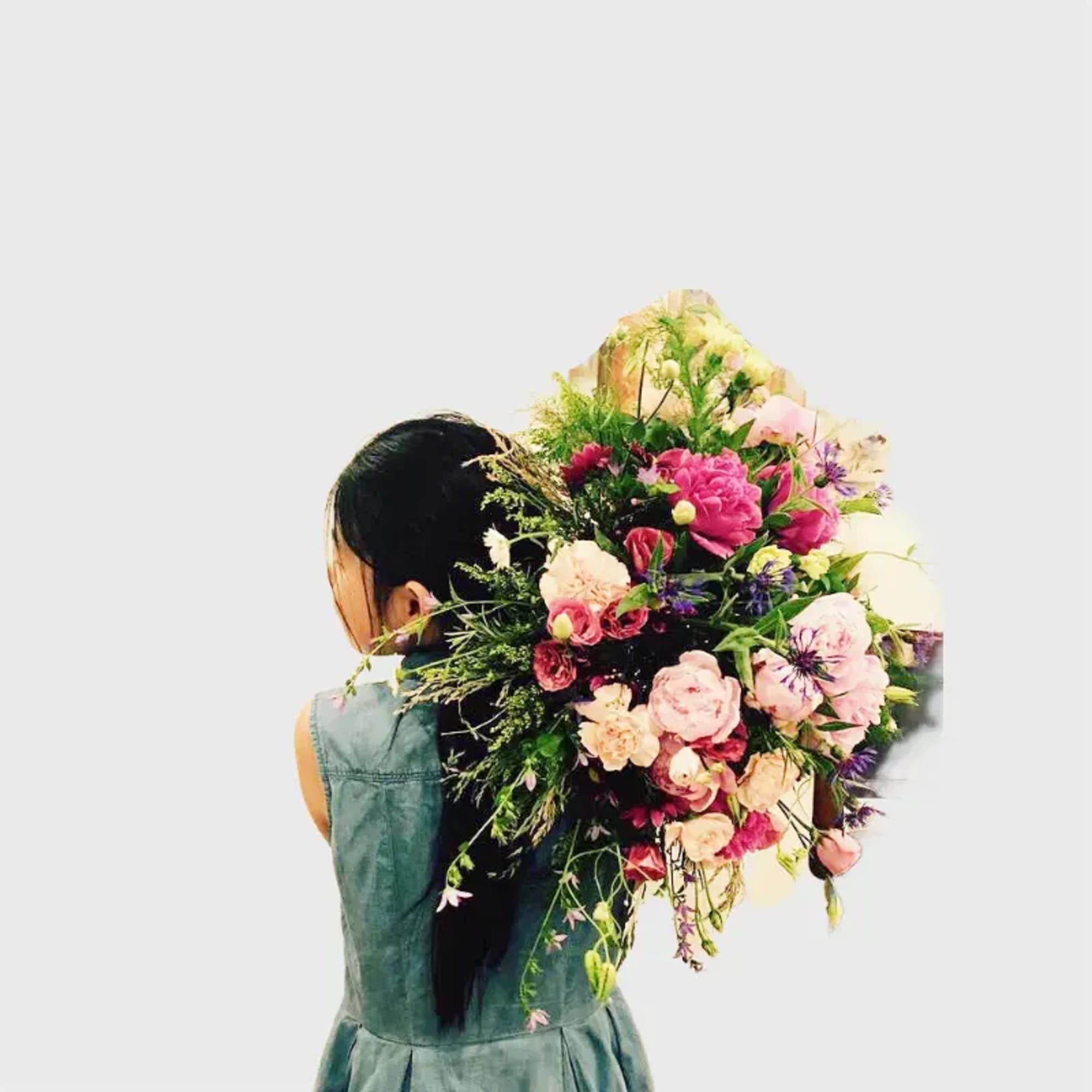 Woman holding a large bouquet of pink and cream flowers over her shoulder