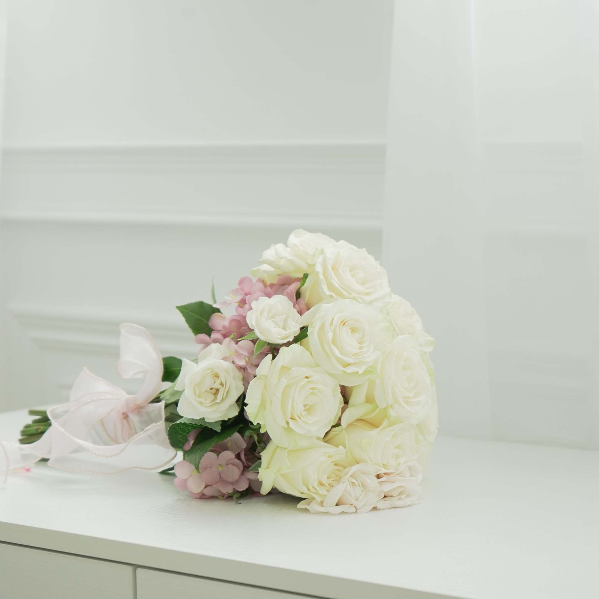 Bouquet of white roses and pale pink flowers tied with a white ribbon