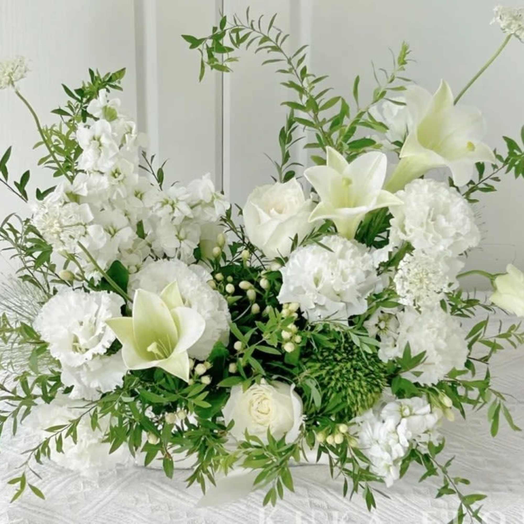 White floral arrangement with lilies and carnations in a low design
