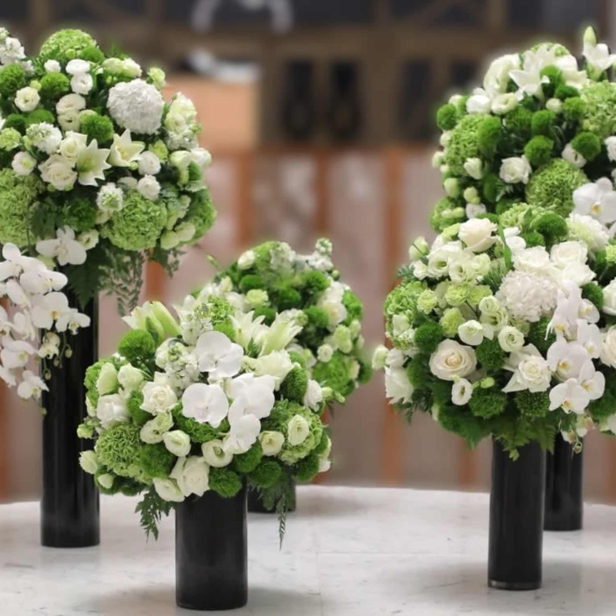 Green and white floral arrangements in tall black vases