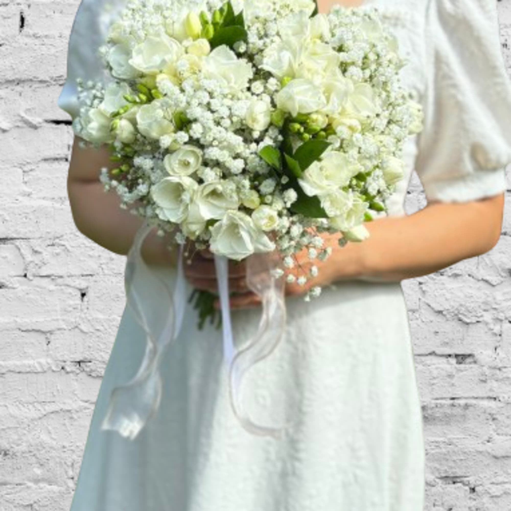 Bride holding a white bouquet with ribbon streamers