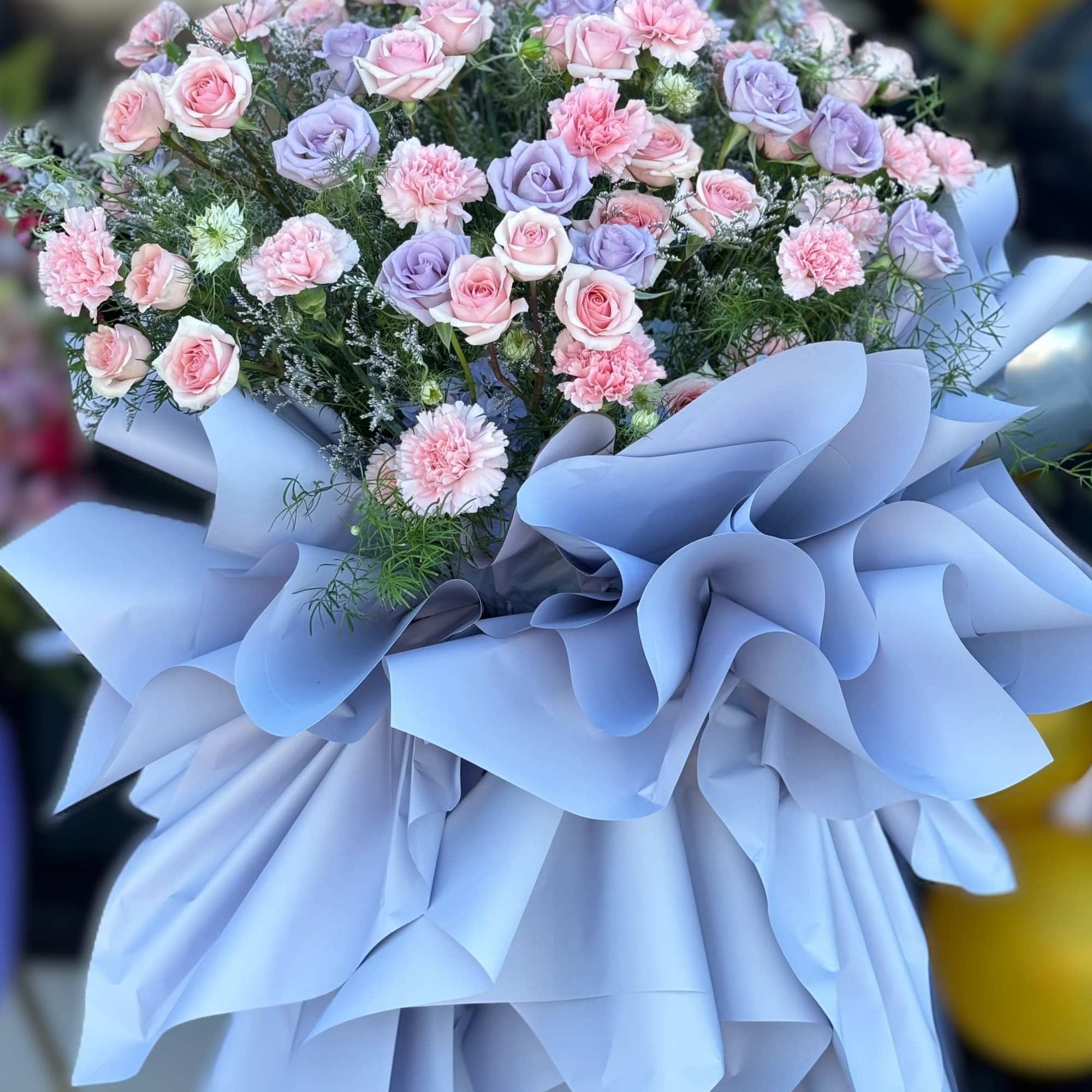 Bouquet of pink and lavender roses with carnations wrapped in pale blue paper