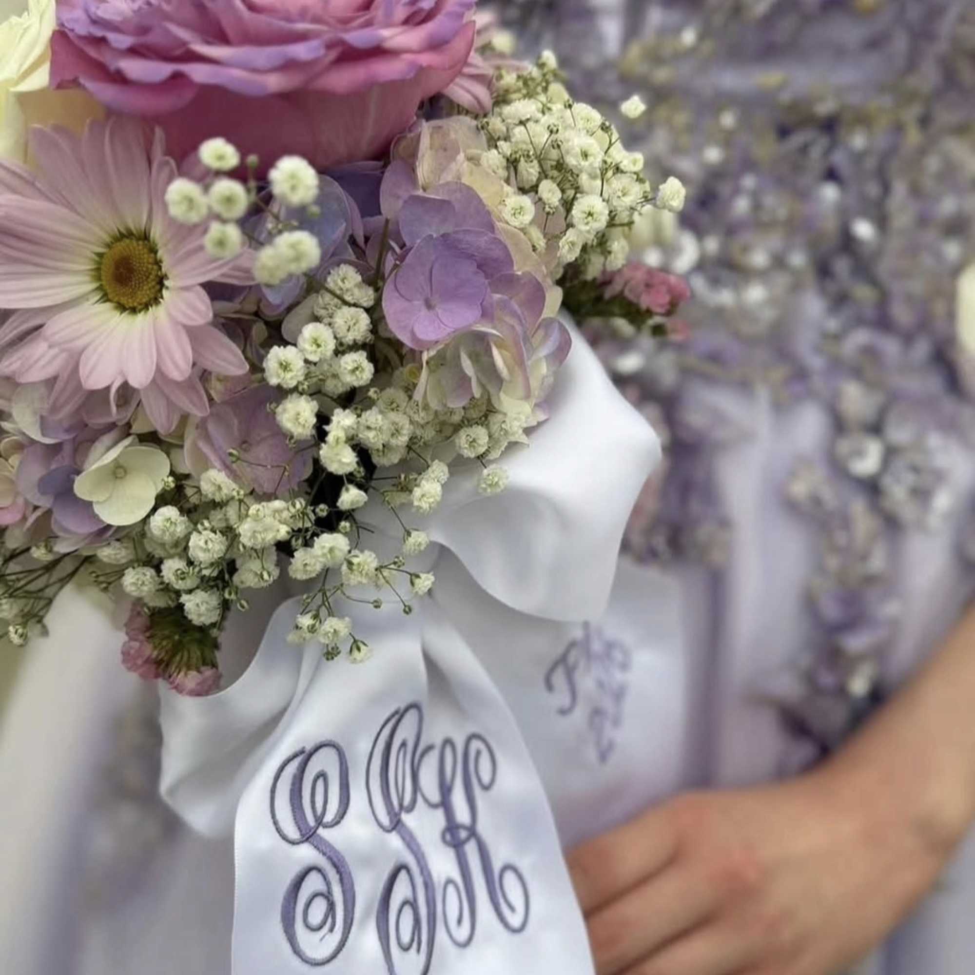 Pastel bouquet with a pink rose, daisy, and baby’s breath tied with a white ribbon