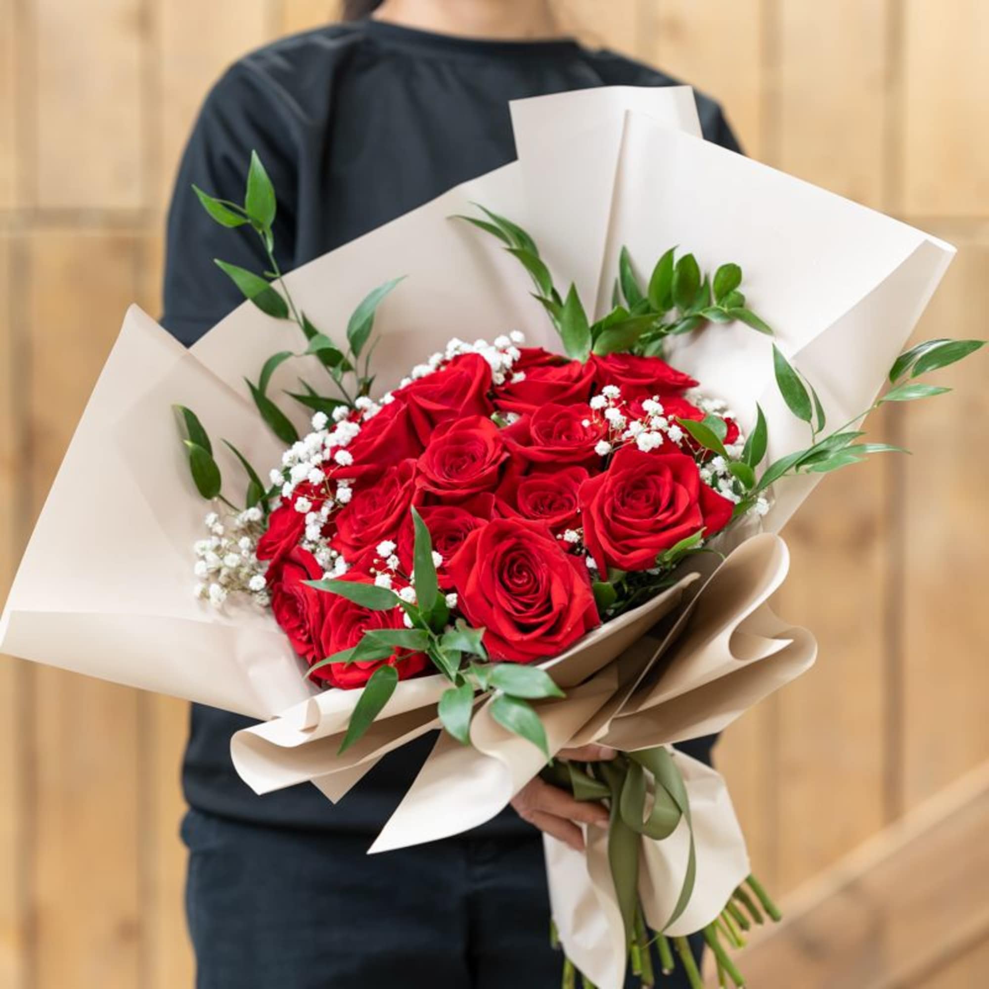 Bouquet of red roses with baby's breath in cream wrapping