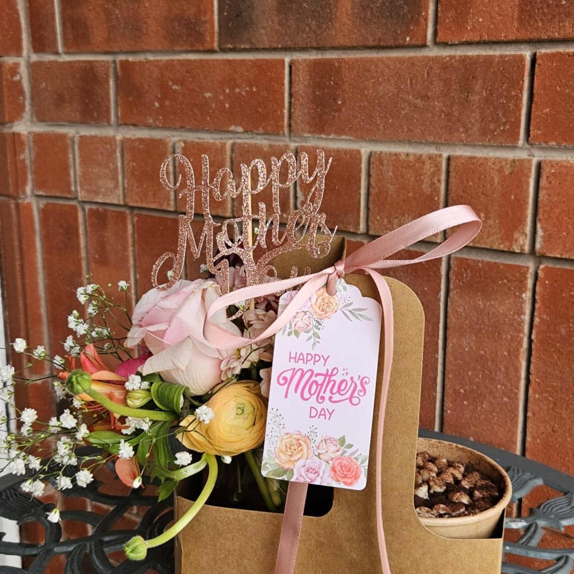 Pink and yellow flower arrangement in a kraft gift bag with a Mother's Day tag