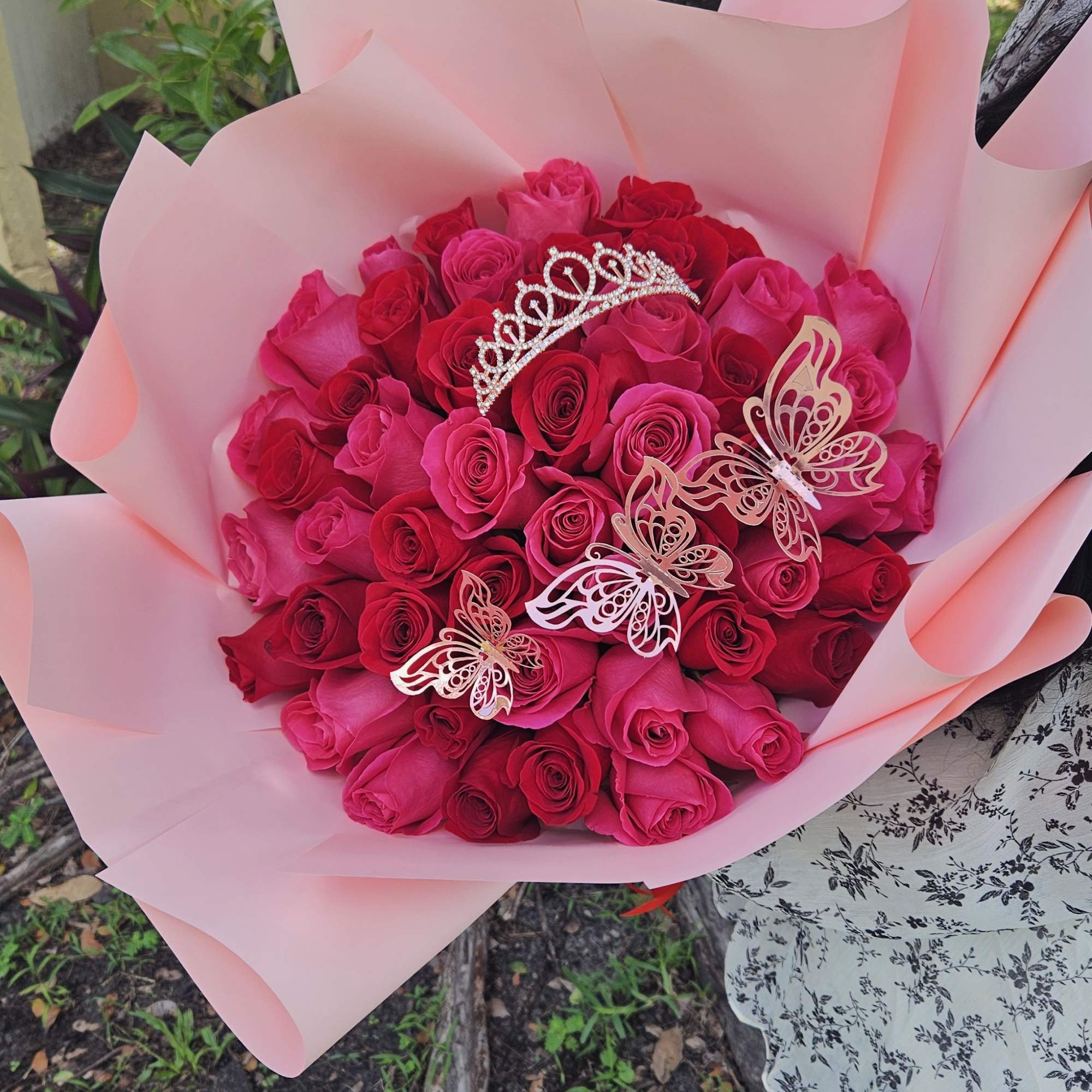 Large bouquet of hot pink roses wrapped in pale pink paper with butterfly picks