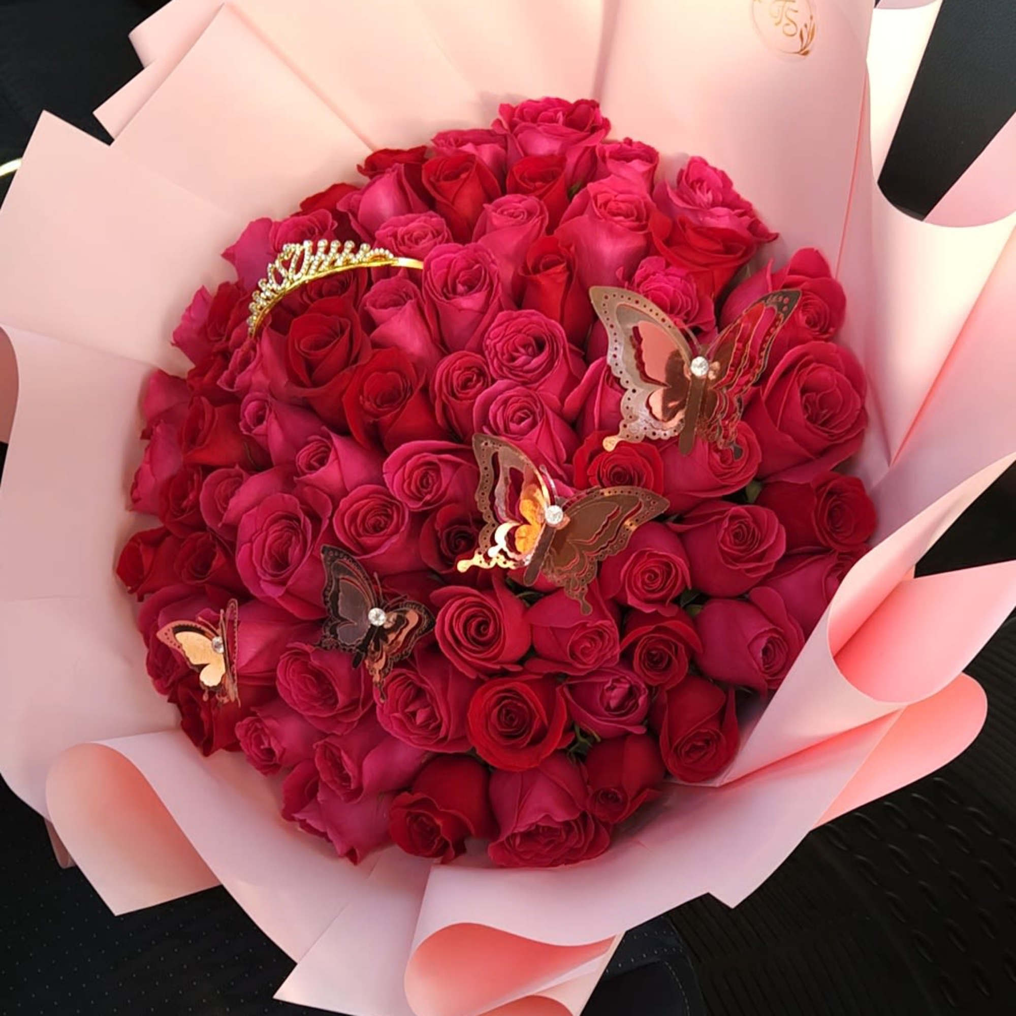 Bouquet of red and pink roses wrapped in pale pink paper with butterfly decorations
