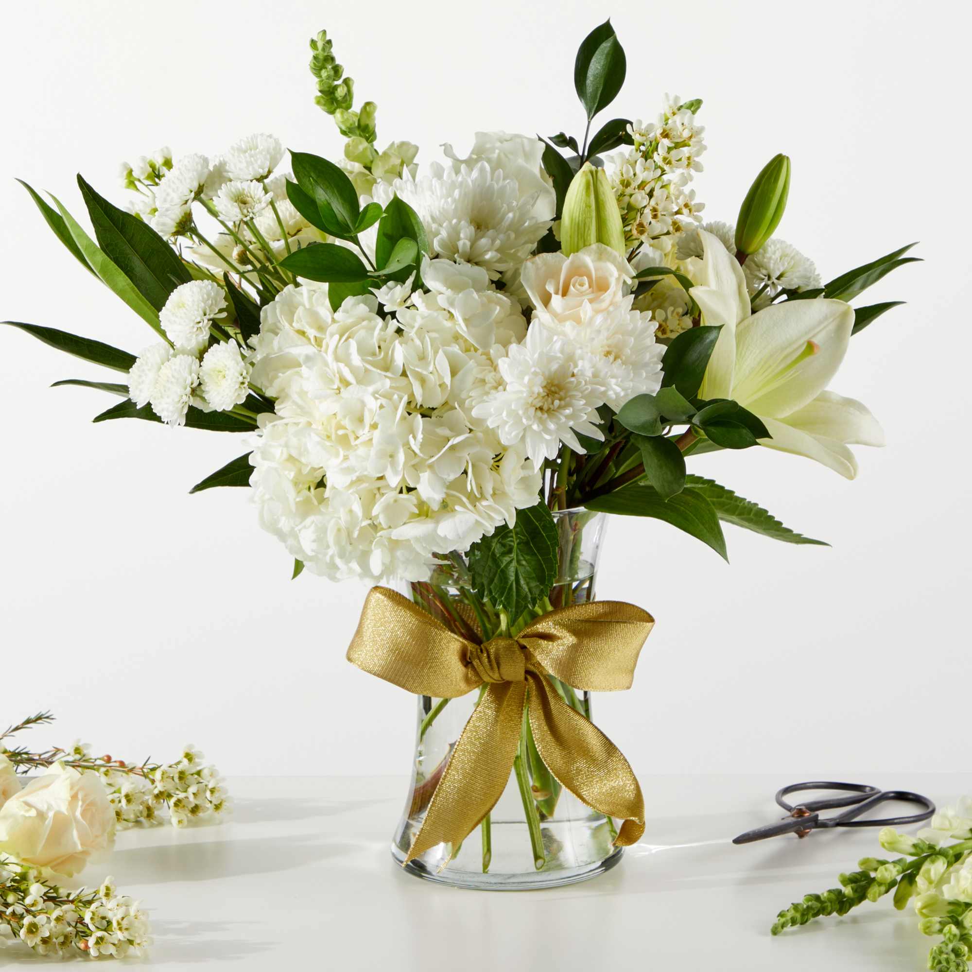 White floral bouquet in a glass vase with a gold ribbon
