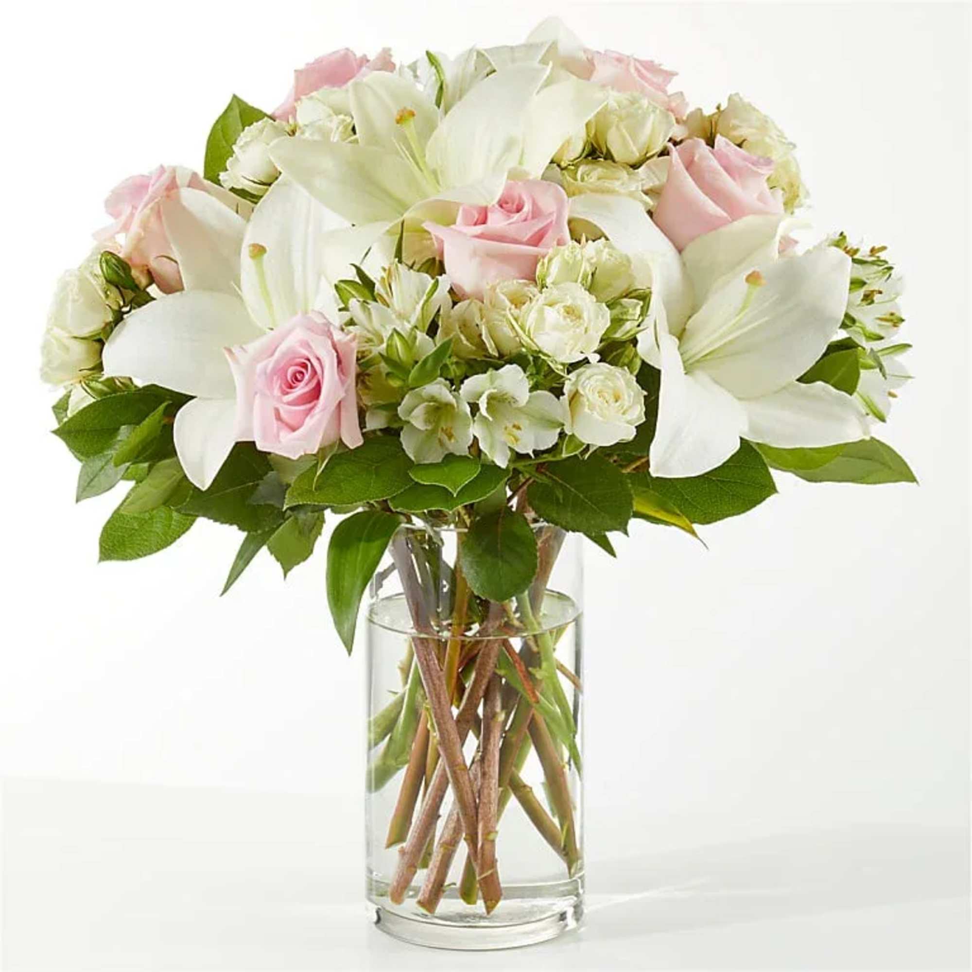 Pink roses and white lilies arranged in a clear glass vase