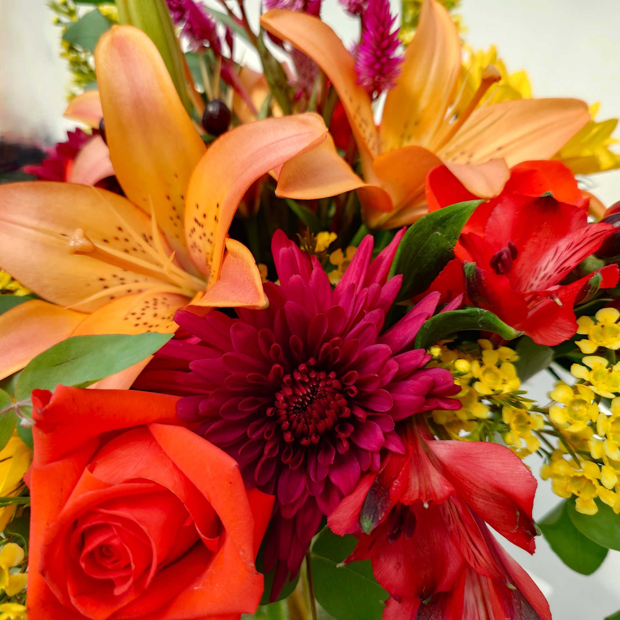 Bright mixed bouquet with orange lilies, red roses, and magenta blooms