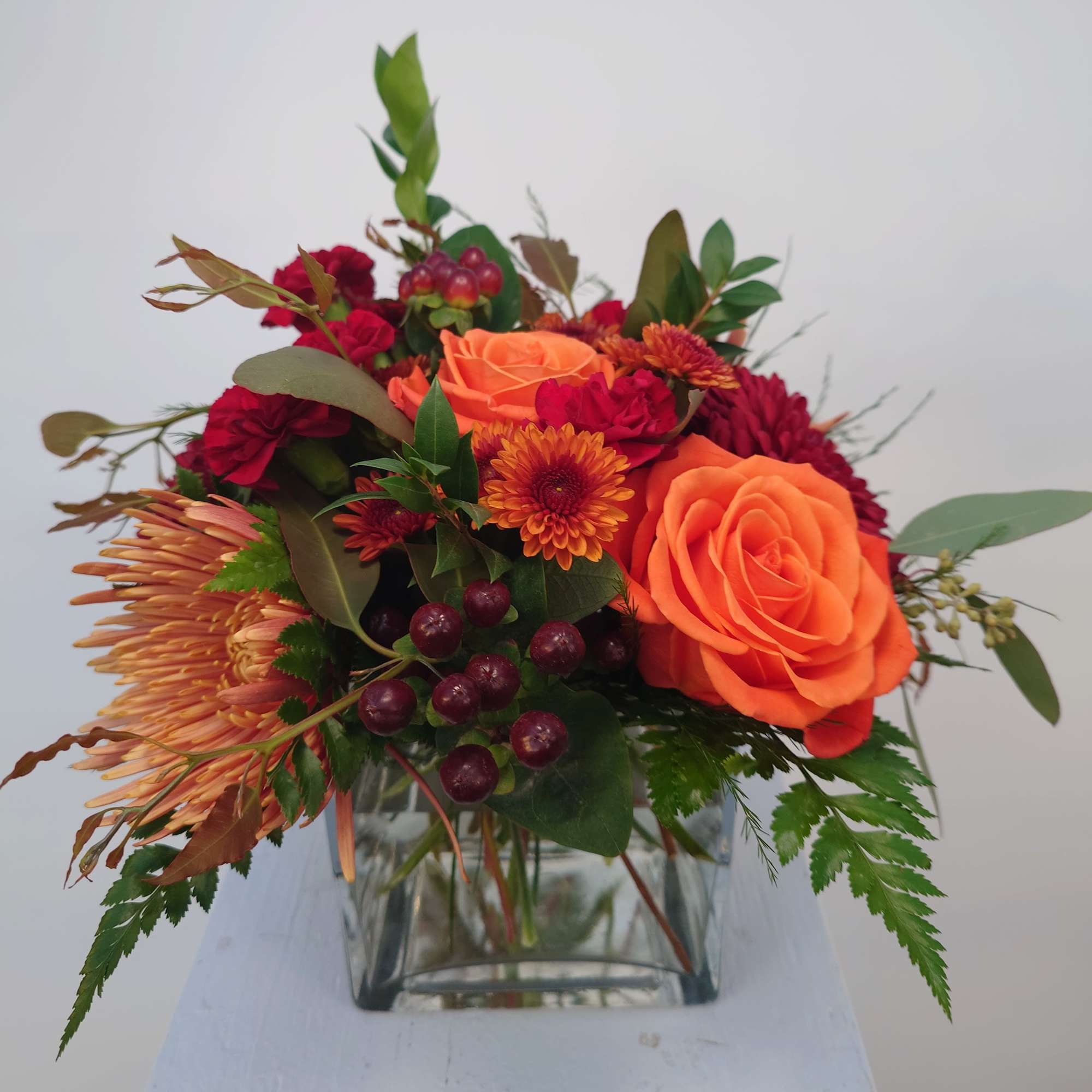 Orange and red mixed bouquet in a clear glass vase