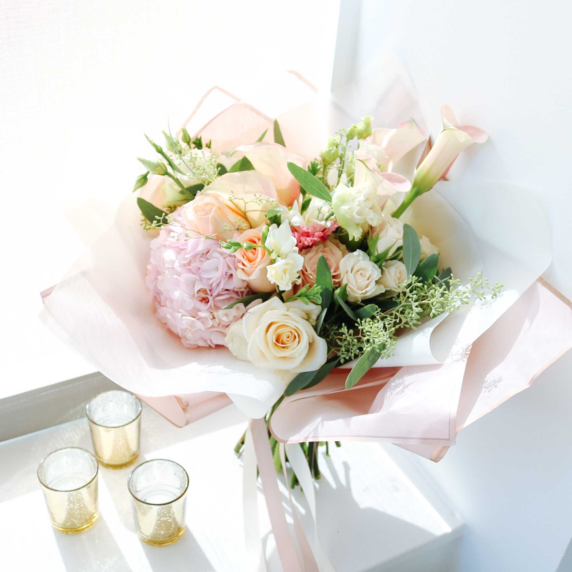 A sumptuous bouquet of delicate calla lilies, elegant pink hydrangea, and graceful