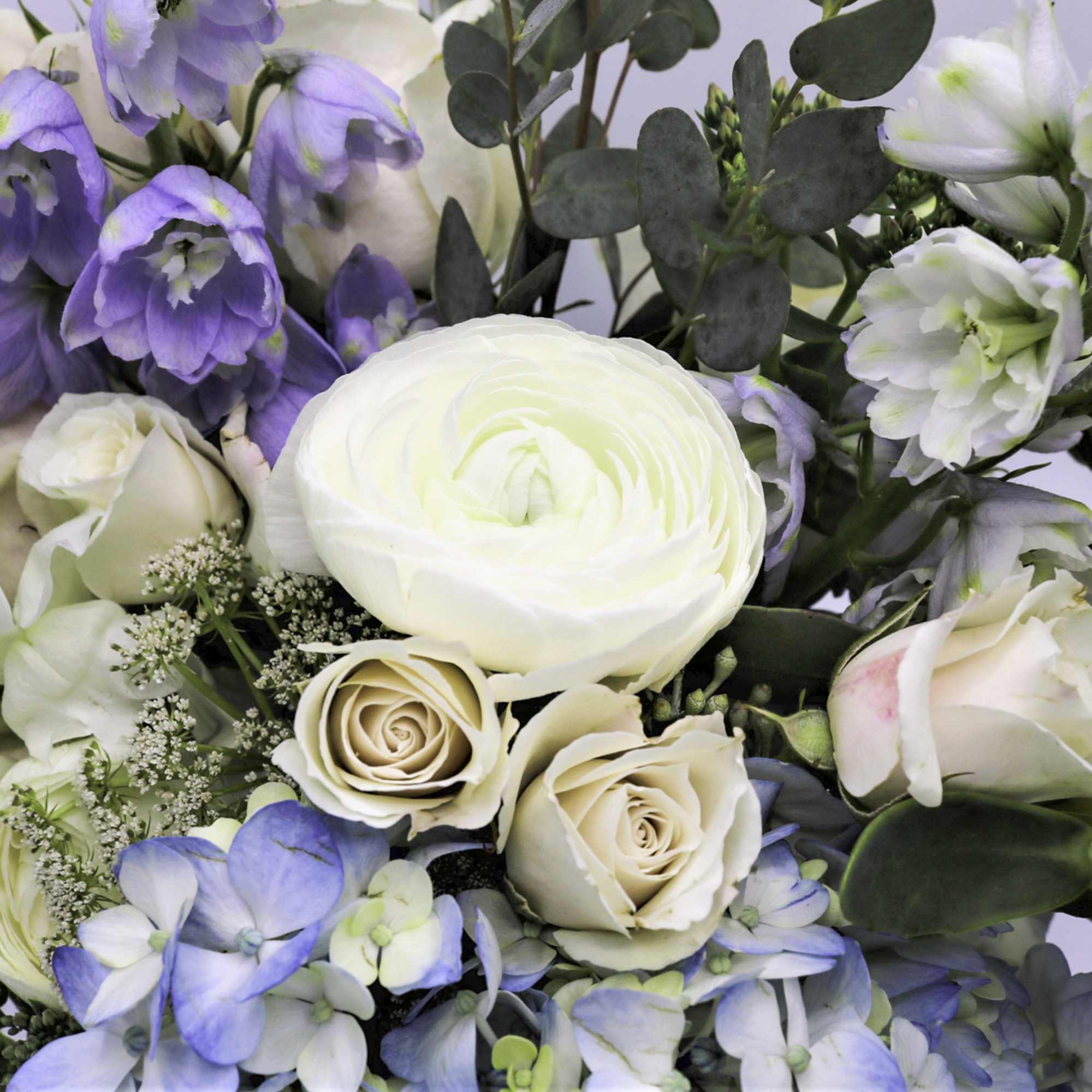 Bouquet of white and pale blue flowers with cream roses