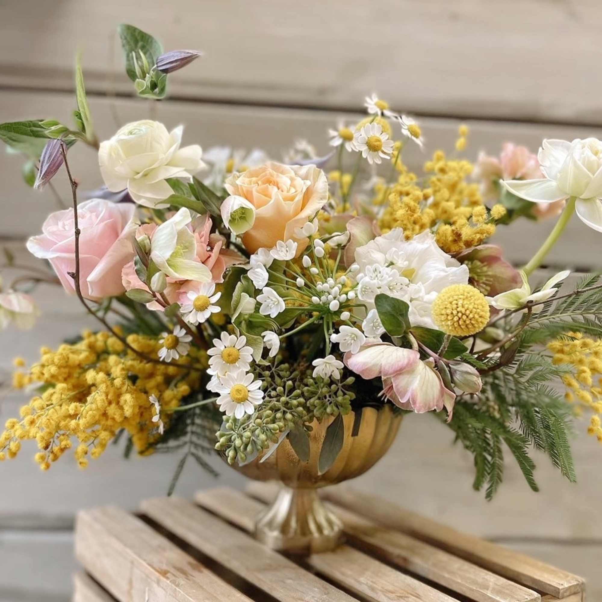 Pastel floral arrangement in a gold pedestal vase