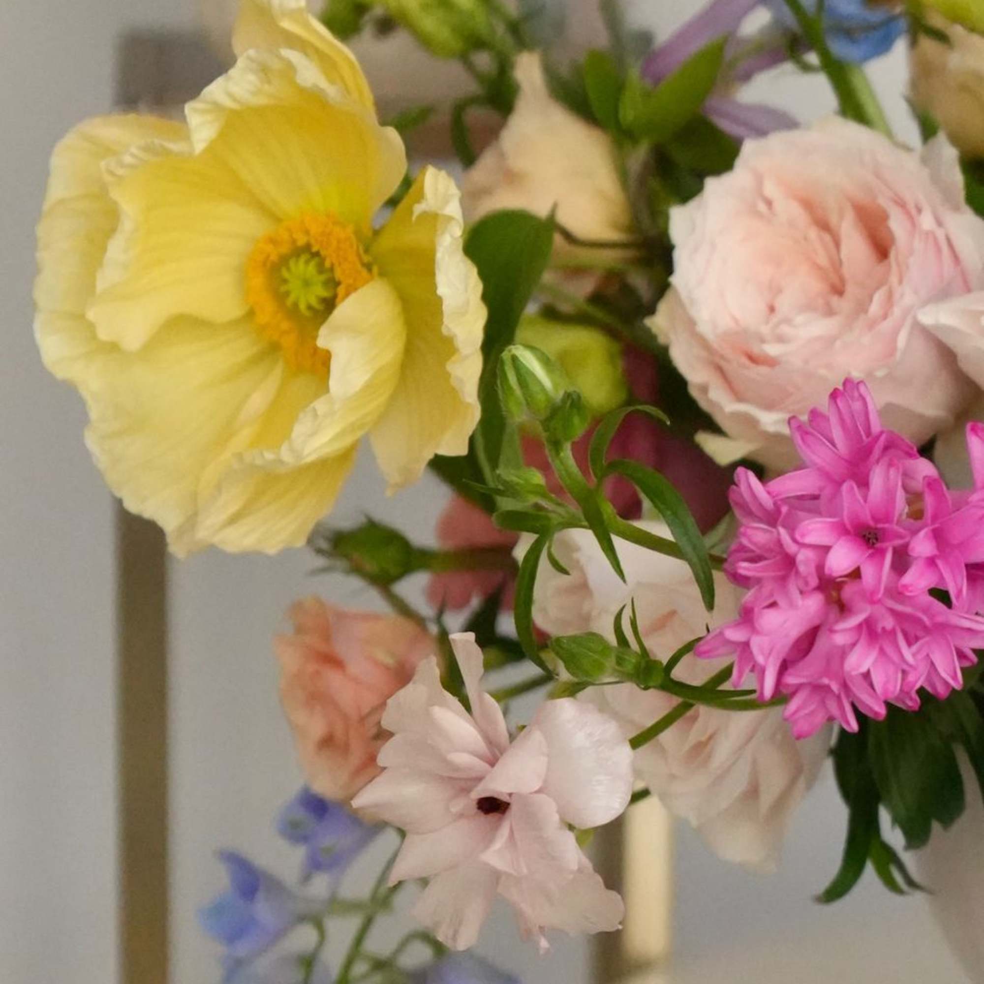 Pastel bouquet with yellow poppy, pink blooms, and blue flowers