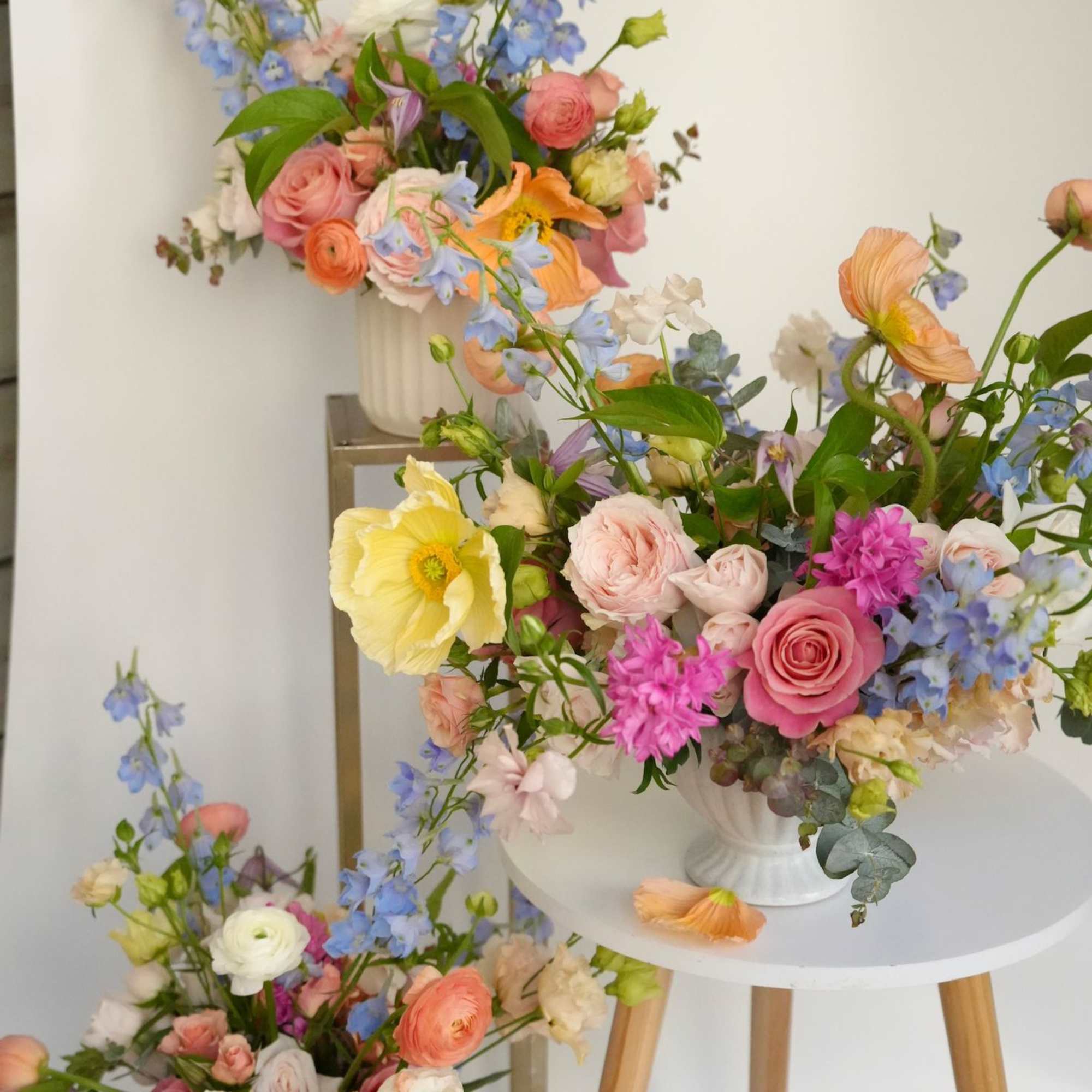 Pastel floral arrangements in white vases with pink, blue, and yellow blooms