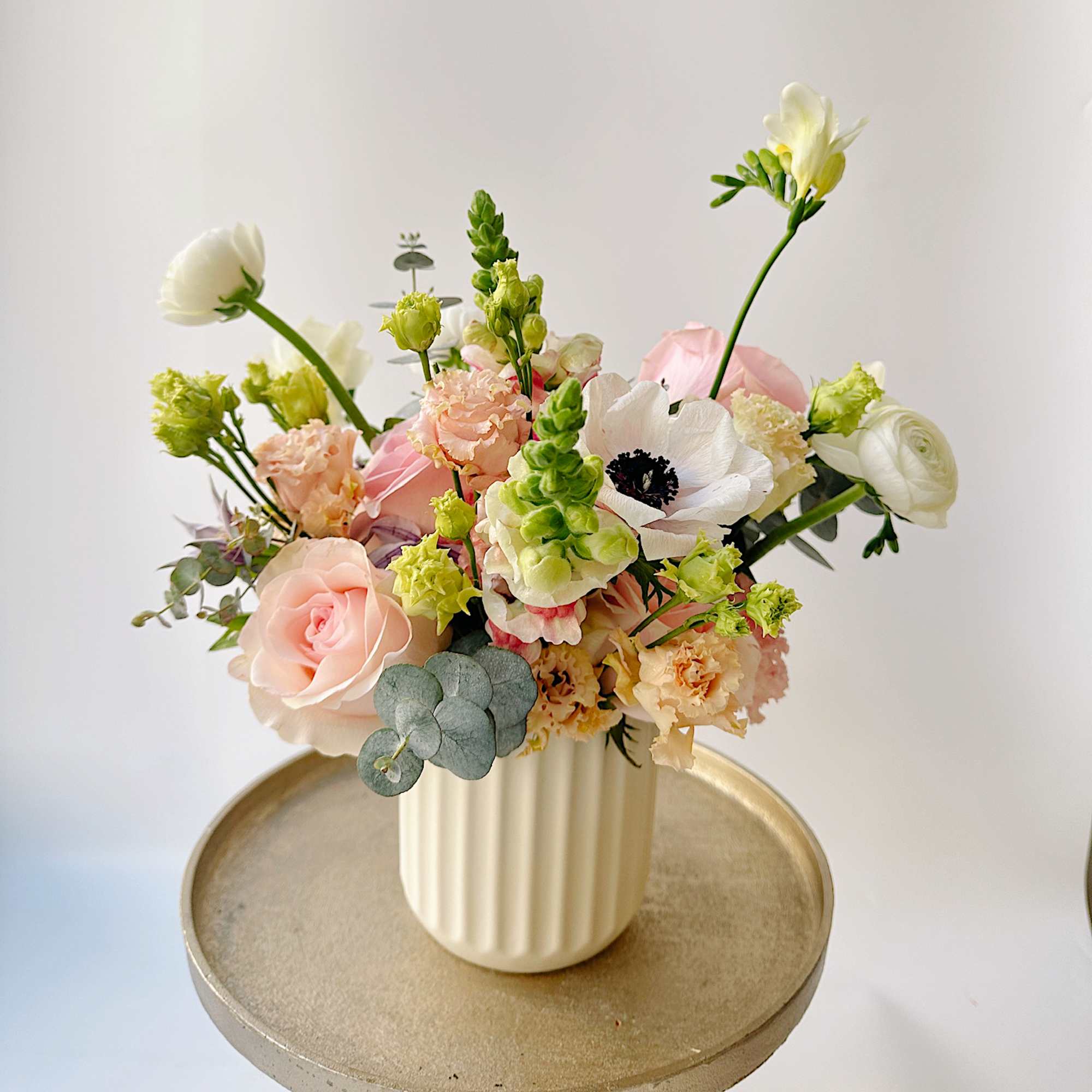Pastel flower arrangement in a ribbed white vase