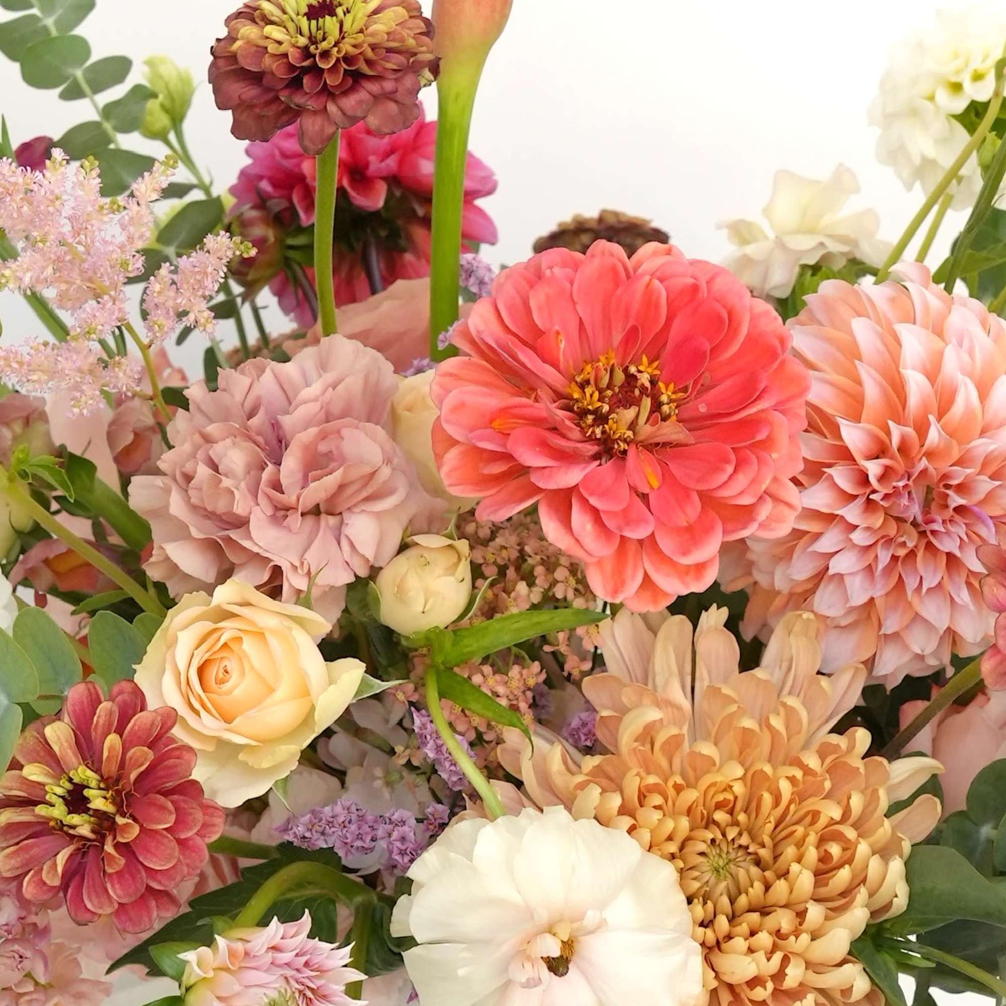 Mixed bouquet with calla lily, zinnias, roses, and chrysanthemums in a white vase