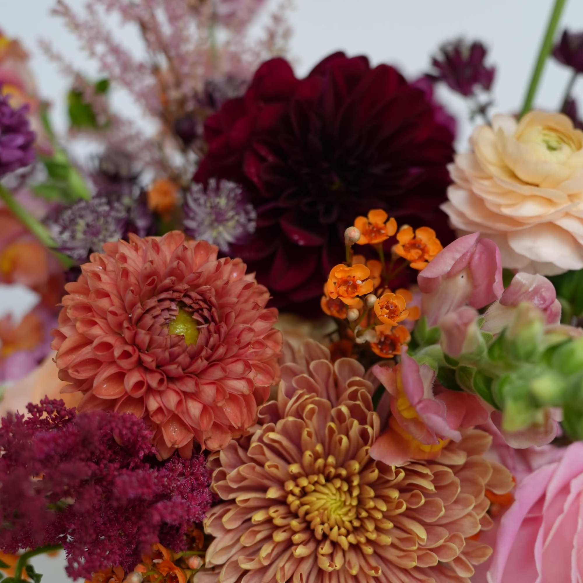 Mixed bouquet of pink, peach, burgundy, and orange flowers in a vase
