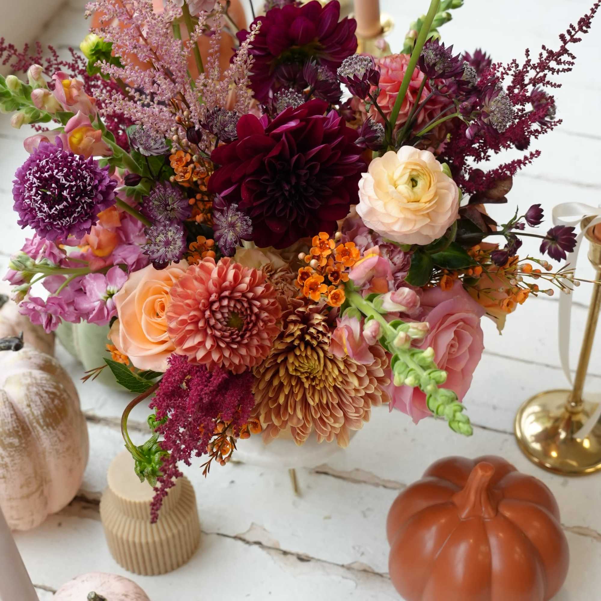 Mixed bouquet of pink, peach, and burgundy flowers in a vase.