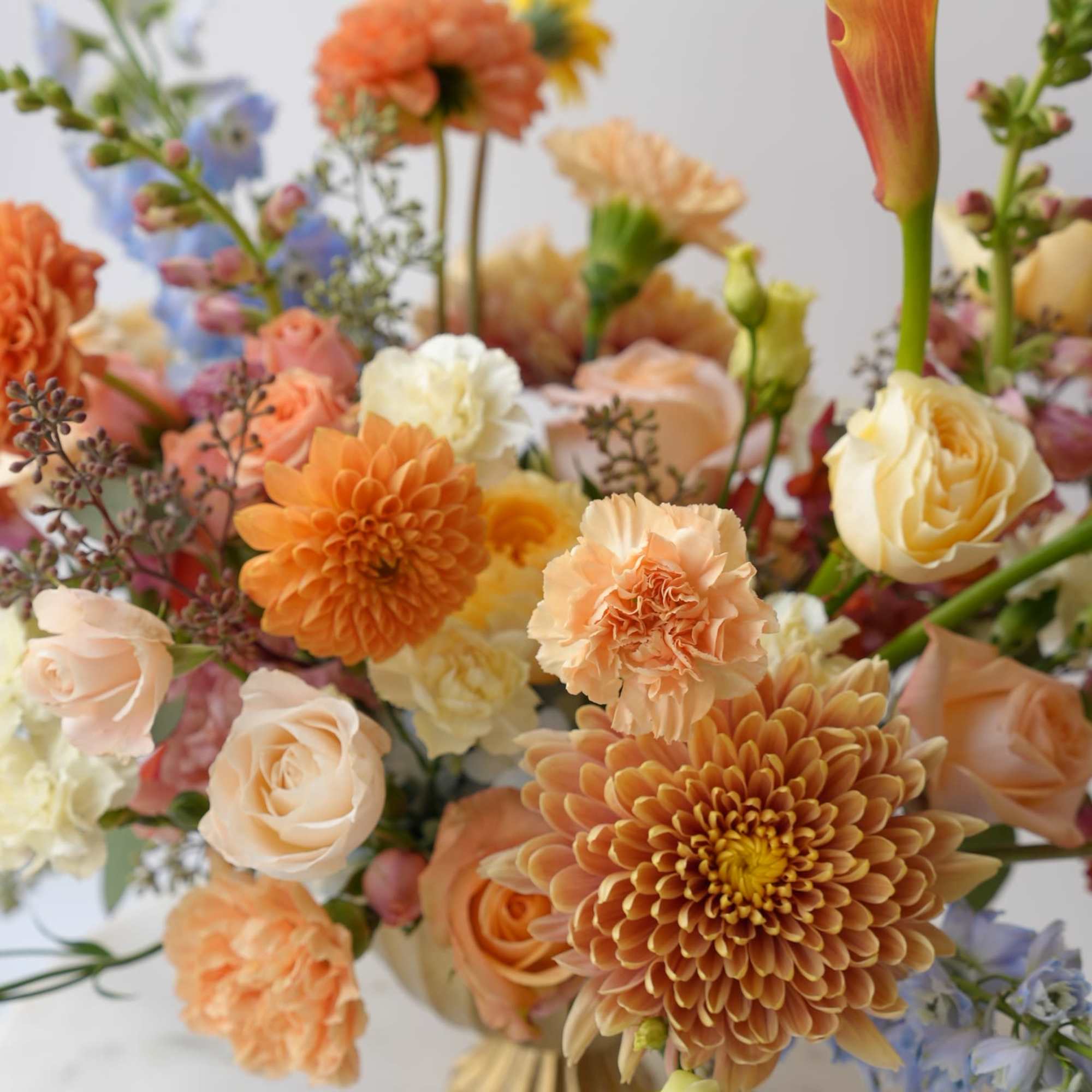 Mixed bouquet of peach, orange, and cream flowers in a gold vase