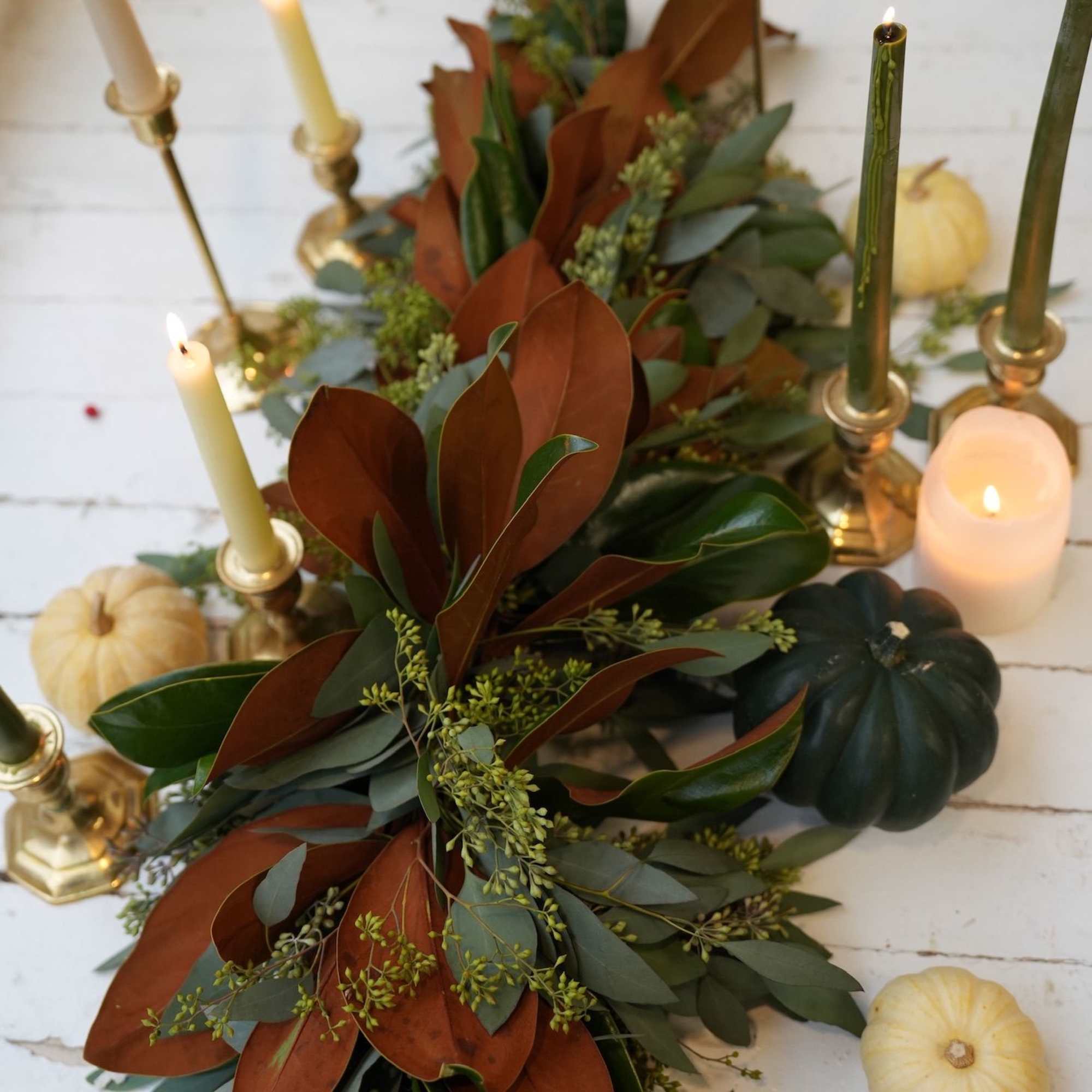 Autumn garland with candles and small pumpkins on a white table