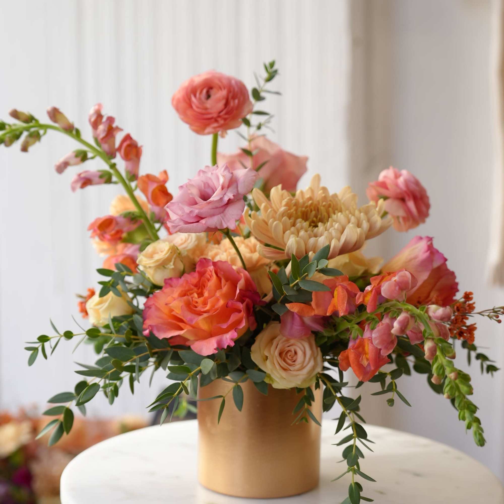 Peach and pink floral arrangement in a gold vase