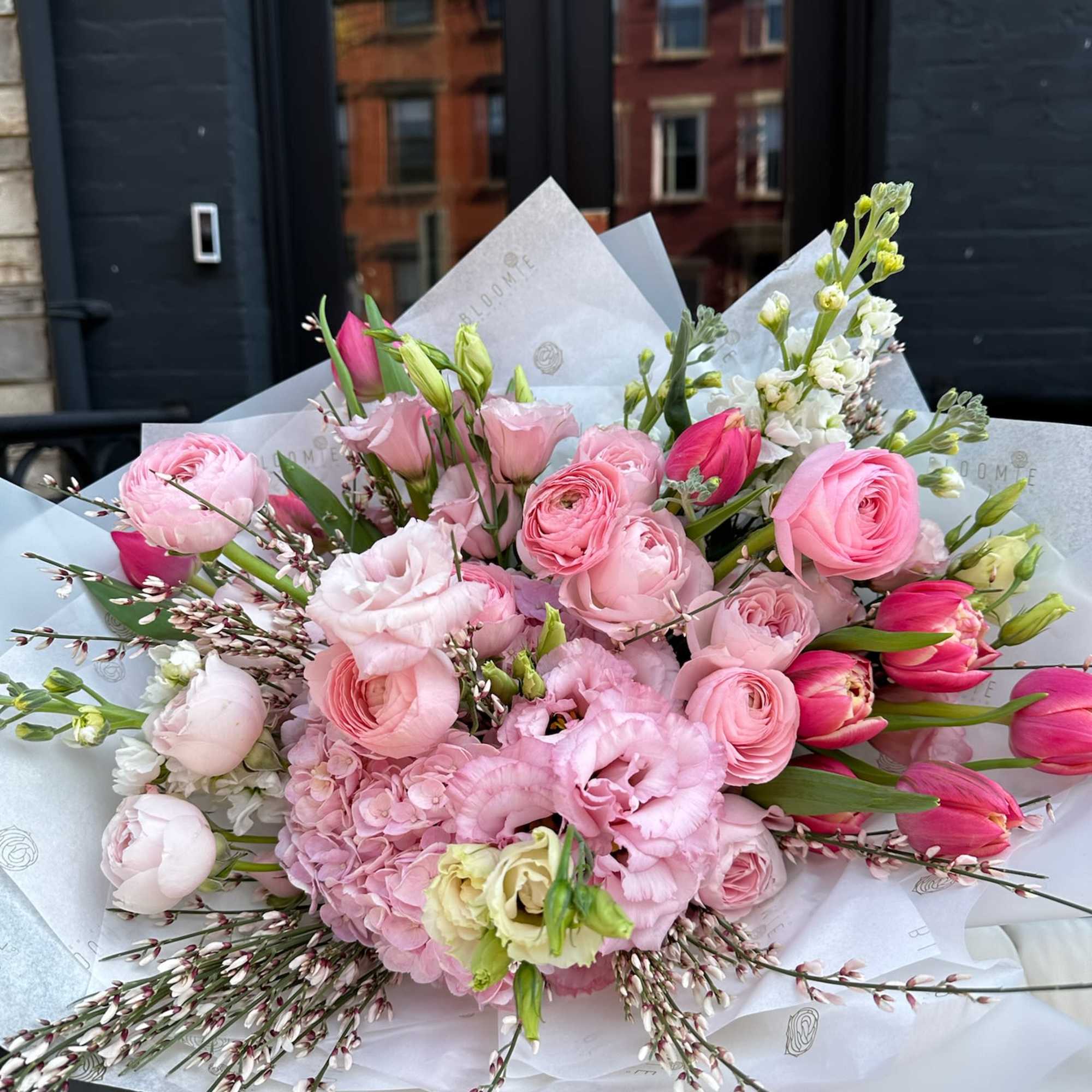 Pink mixed bouquet with ranunculus, tulips, and lisianthus in white wrap