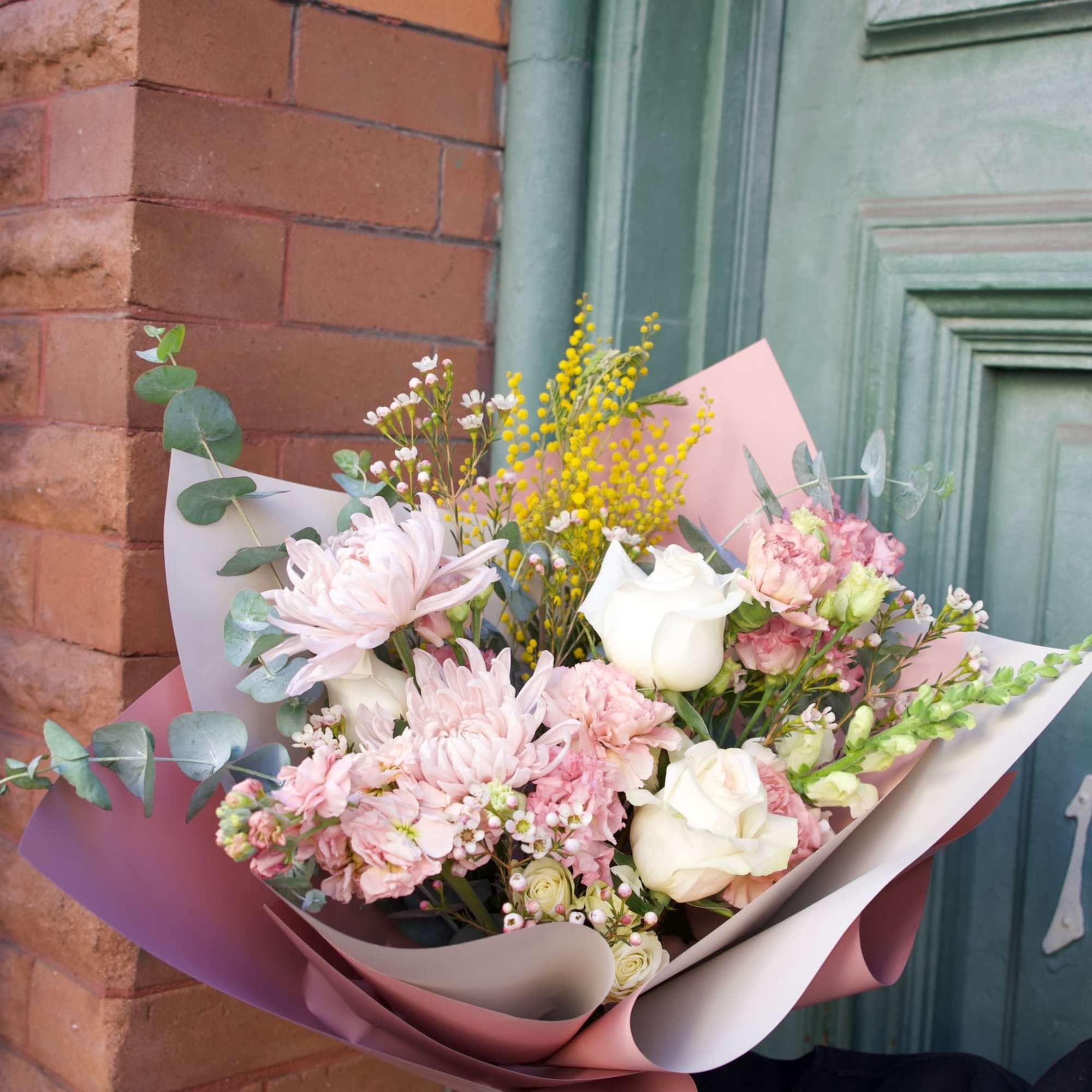 Bouquet of pale pink and white flowers wrapped in pink paper