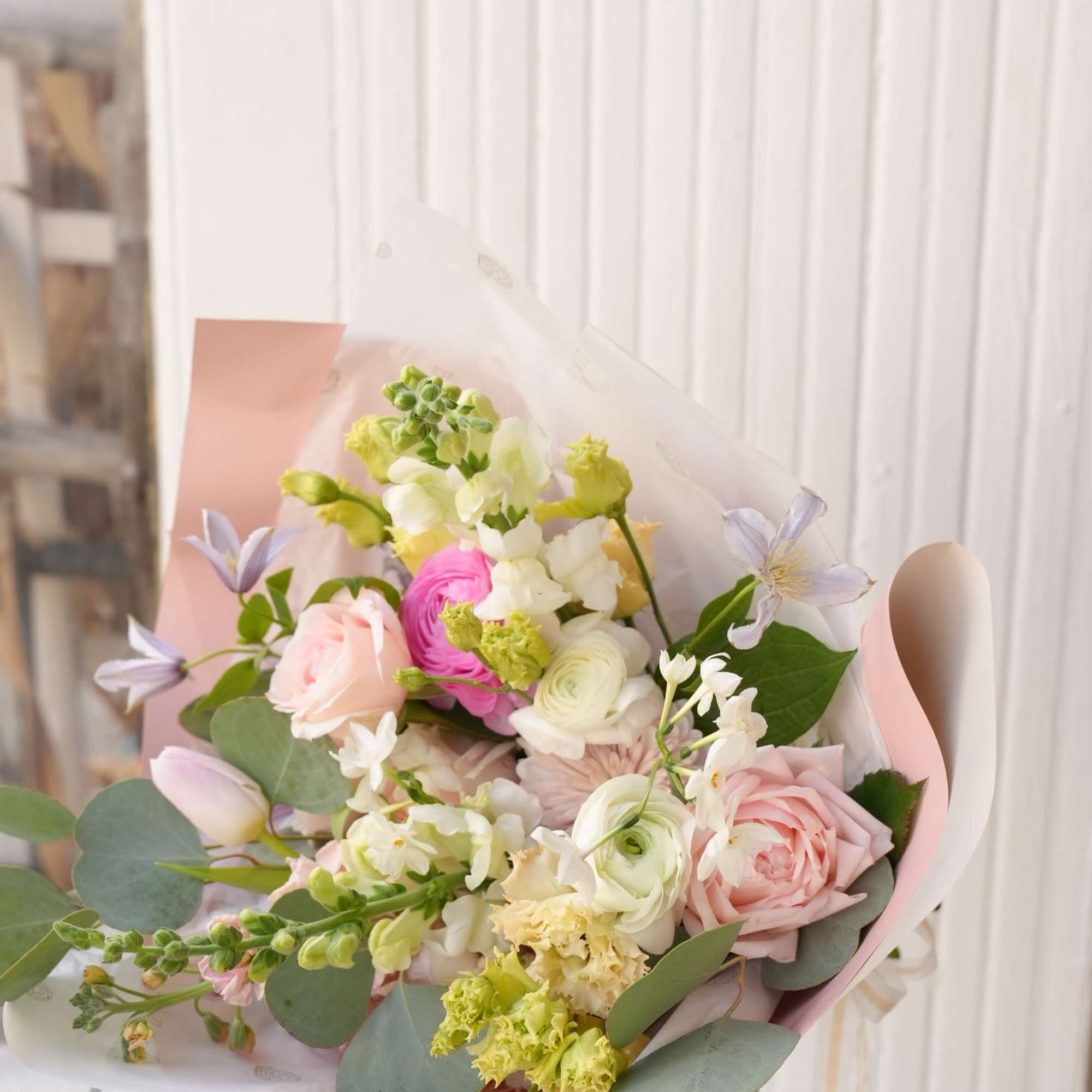 Pastel bouquet of pink, white, and lavender flowers wrapped in pink paper