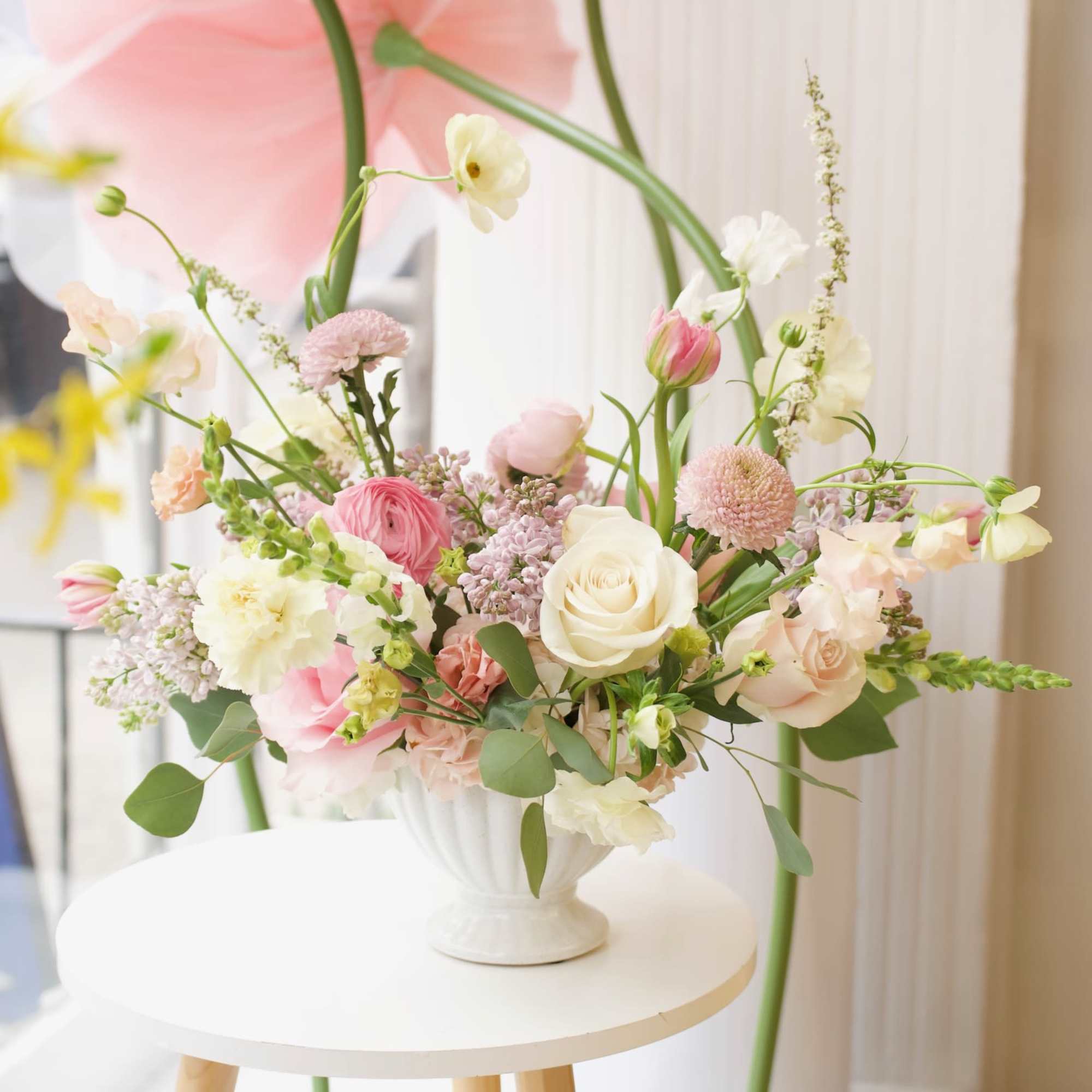 Pastel floral arrangement in a white pedestal vase