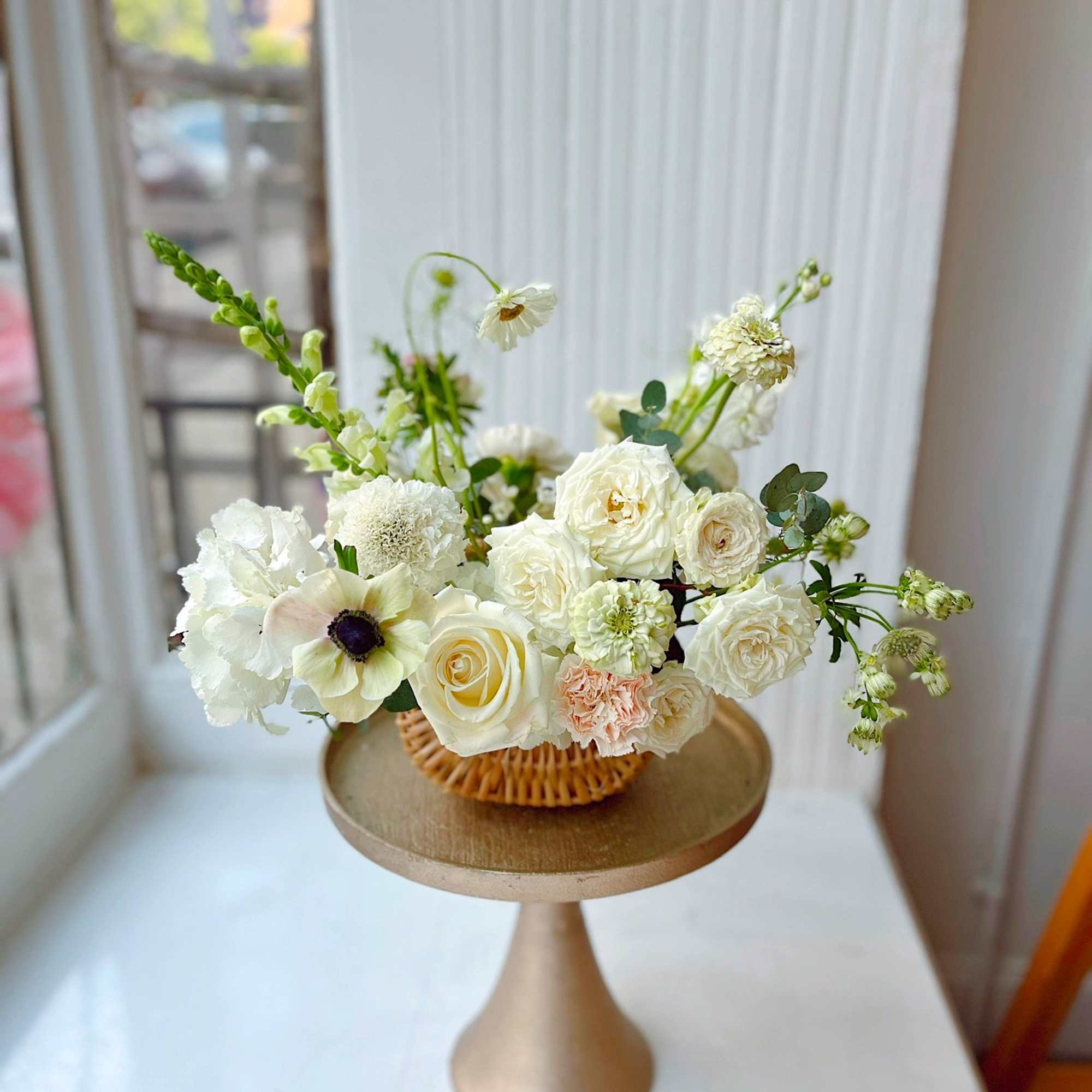 A fresh, garden-style flower basket filled with creamy white roses, seasonal blooms