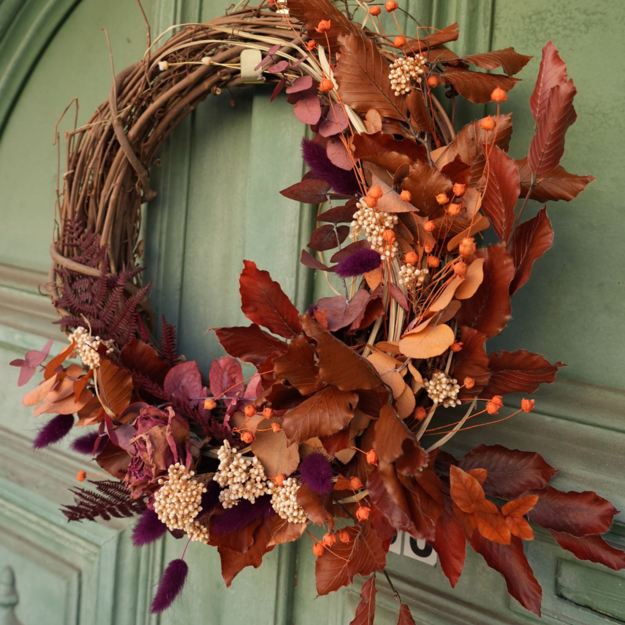Autumn wreath with orange and burgundy leaves on a grapevine base