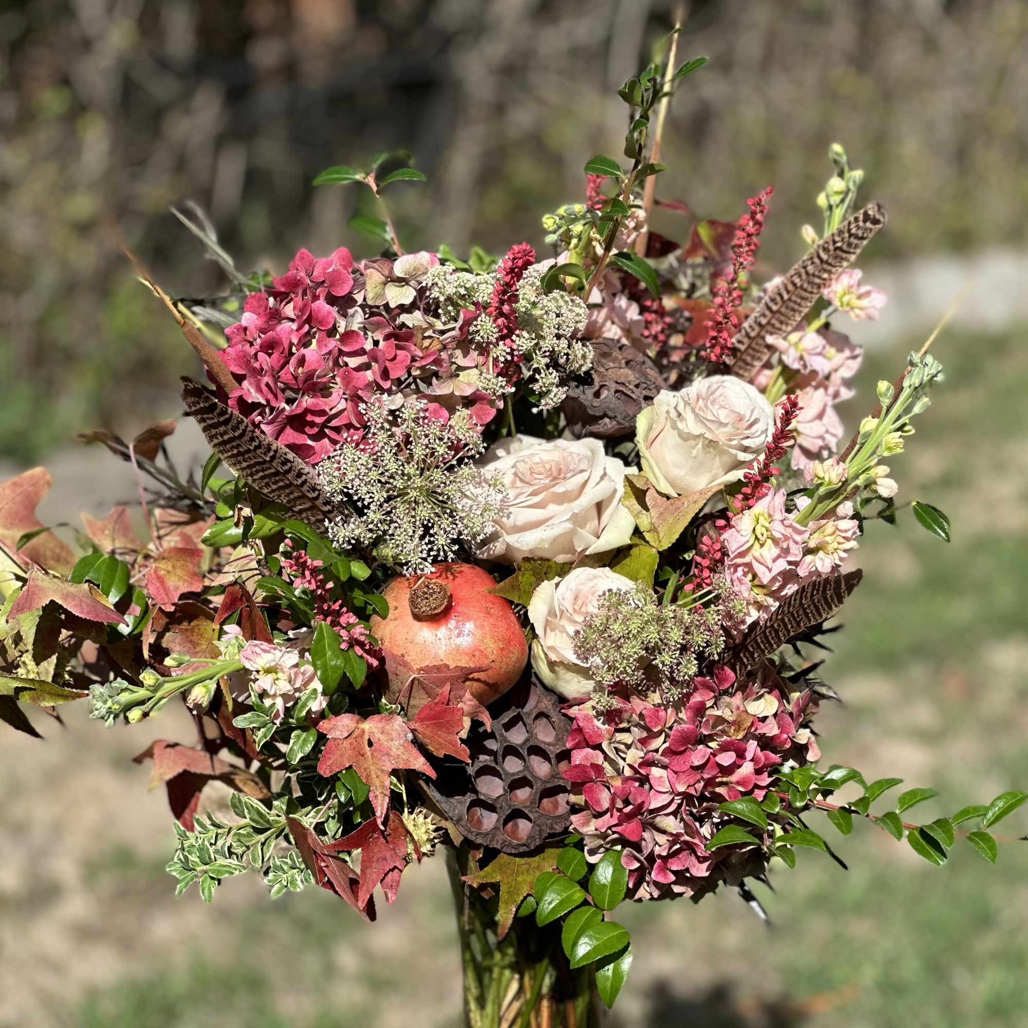 Mixed bouquet with pink hydrangeas, pale roses, and a pomegranate