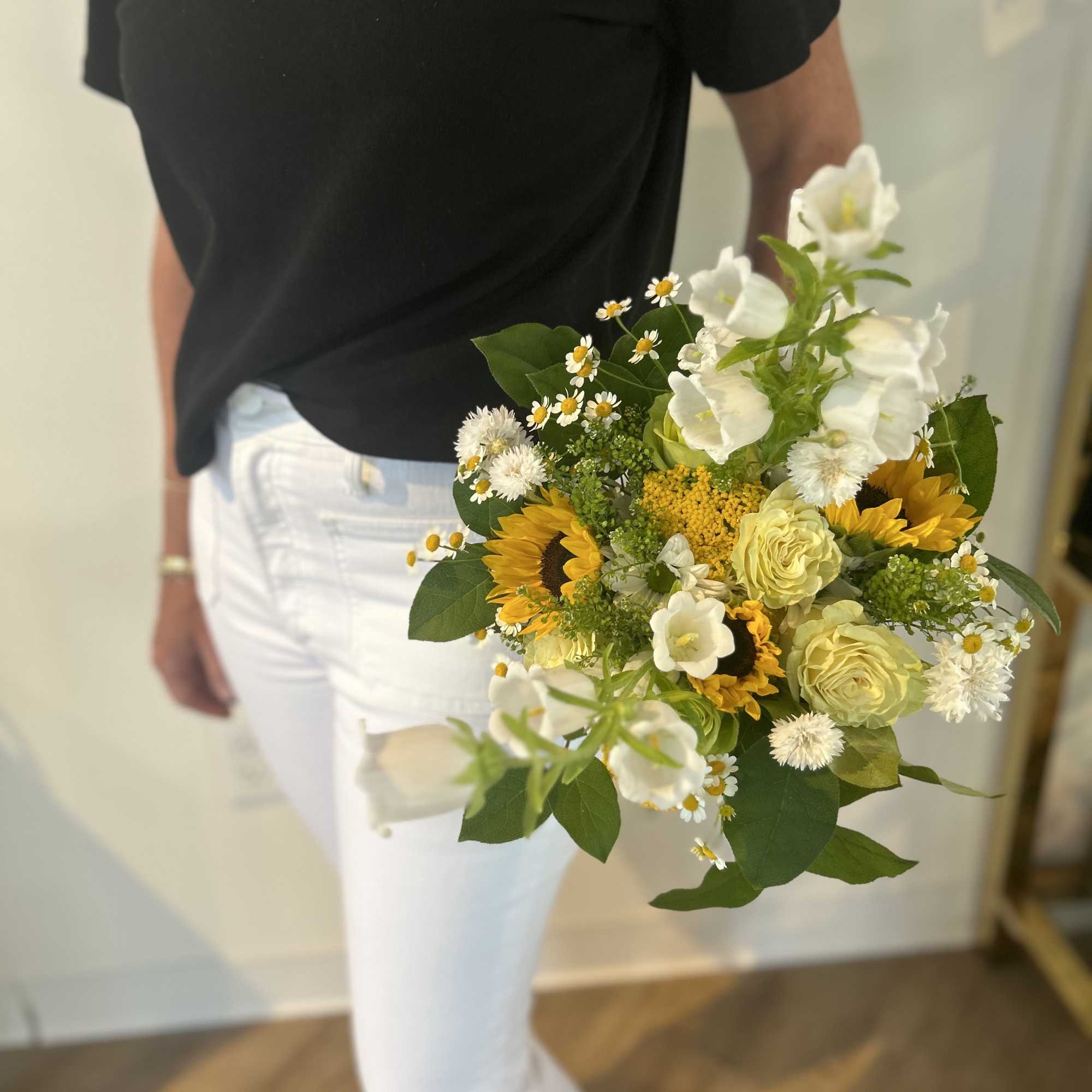 Handheld bouquet with sunflowers, white blooms, and pale yellow roses