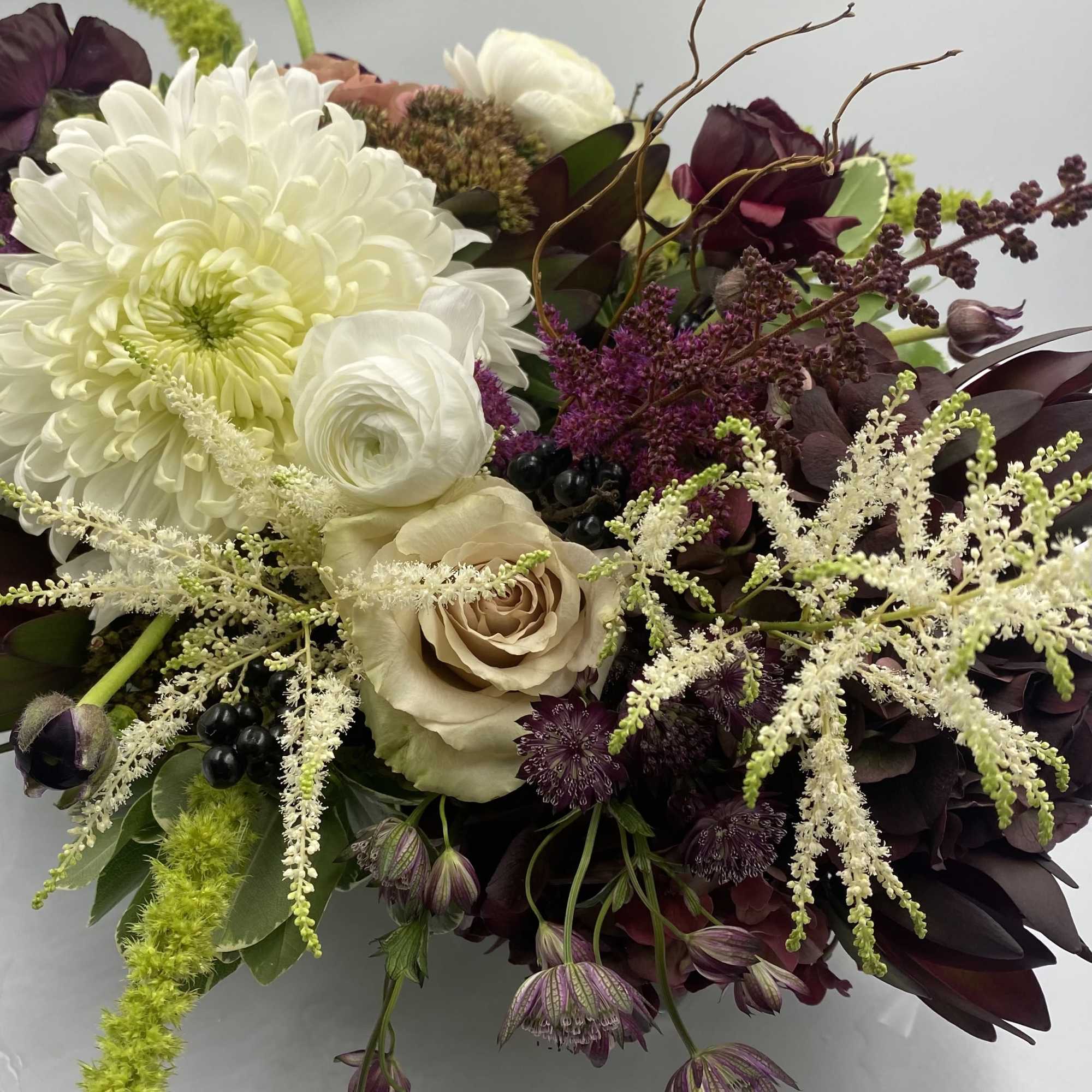 Bouquet of white and burgundy flowers with beige roses and green accents