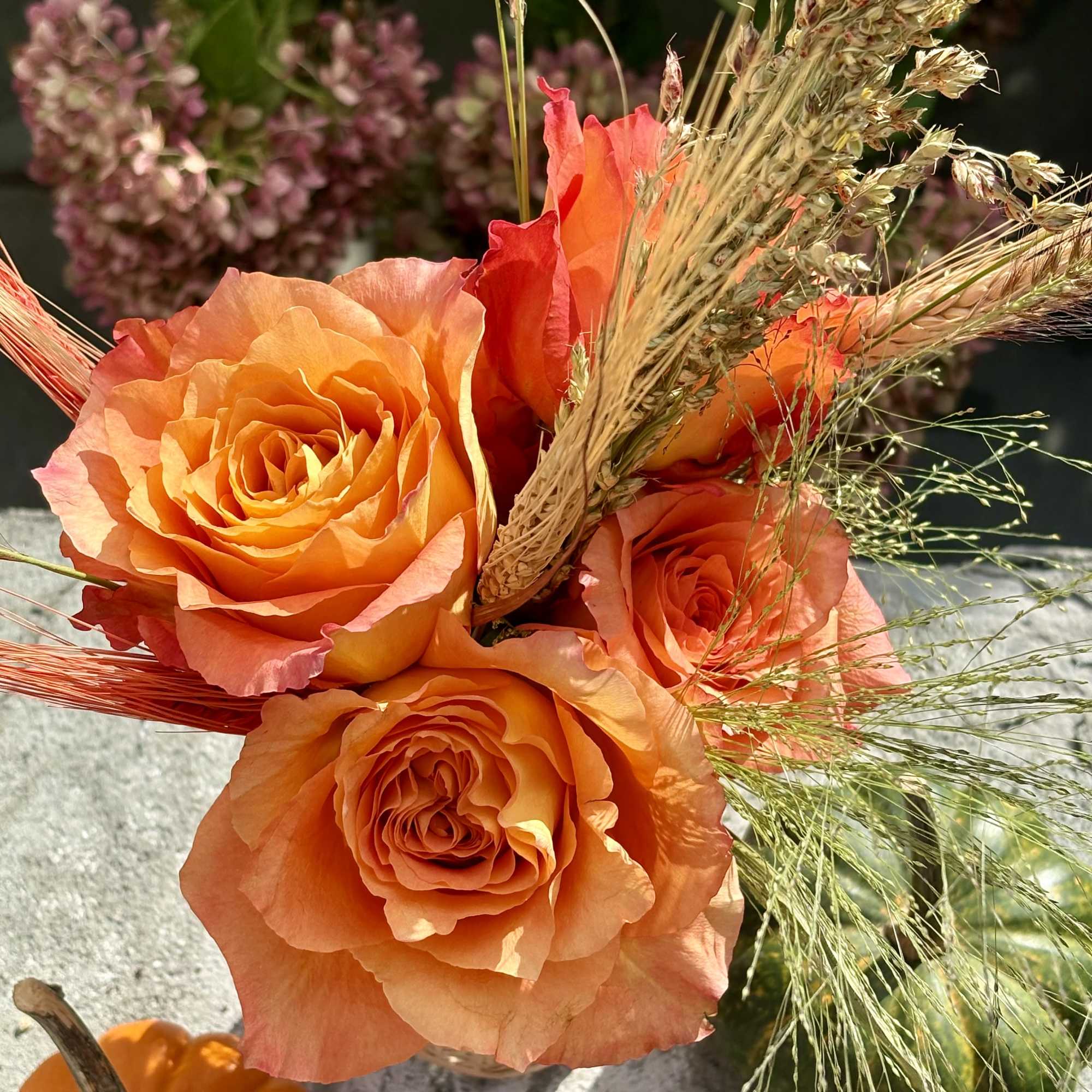 Orange roses with dried grasses and a small pumpkin