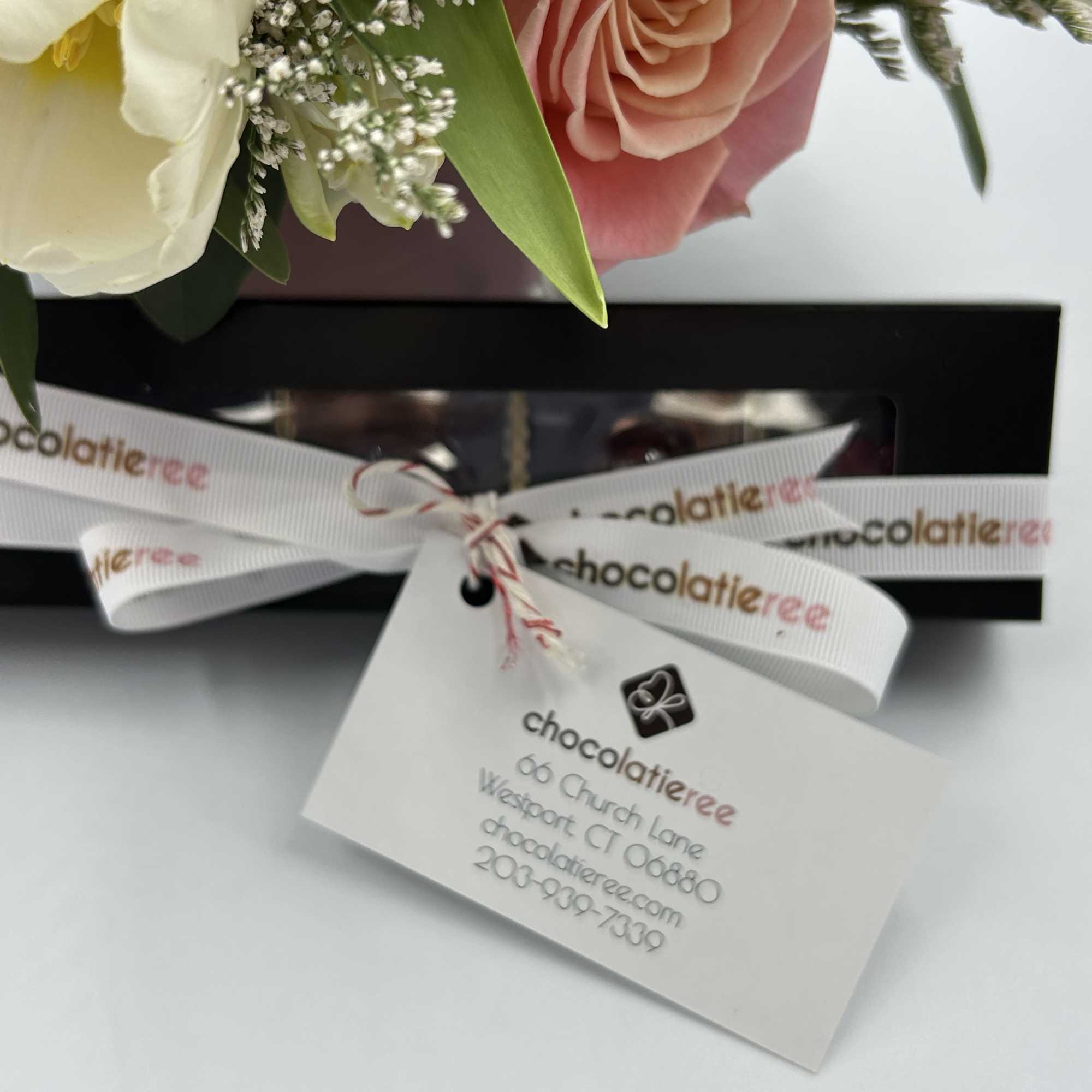 Pink and white flowers with a gift box and branded tag