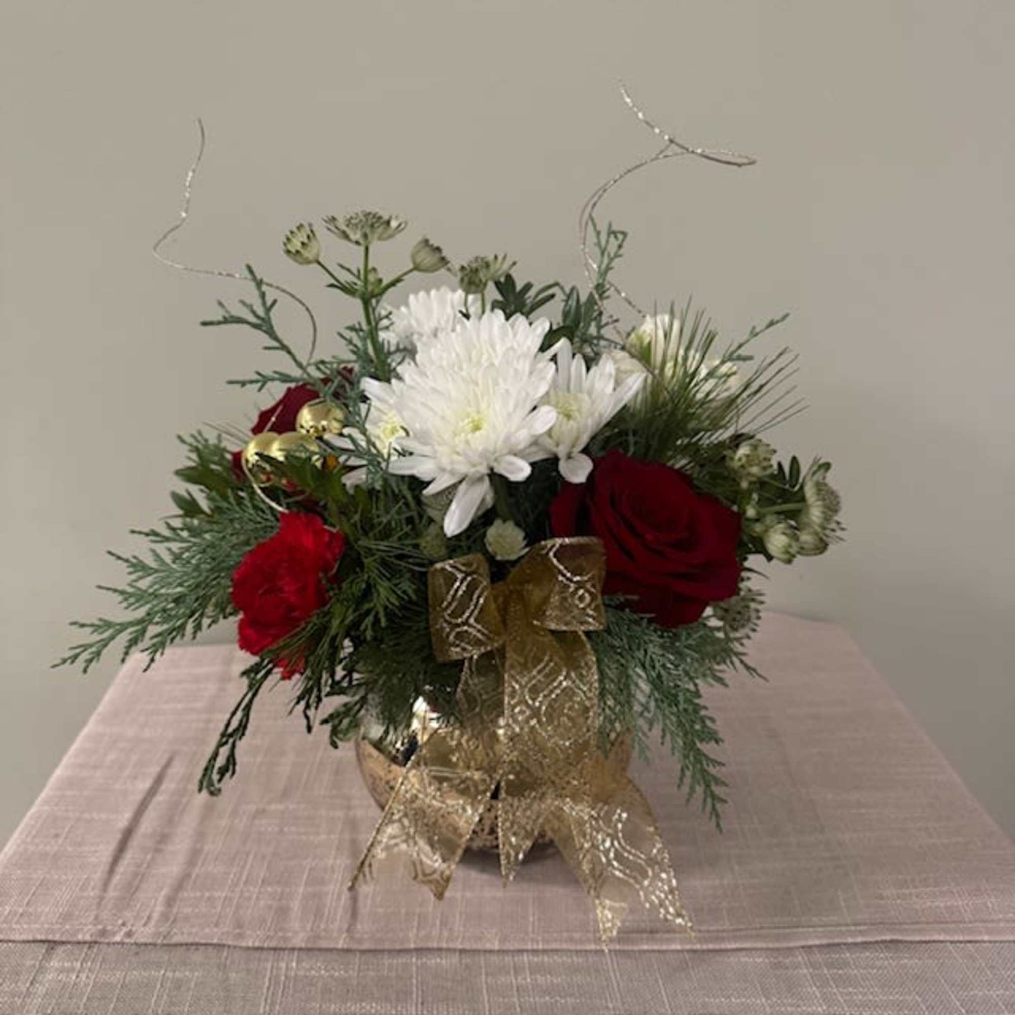 Red roses and white chrysanthemums in a gold vase with a ribbon