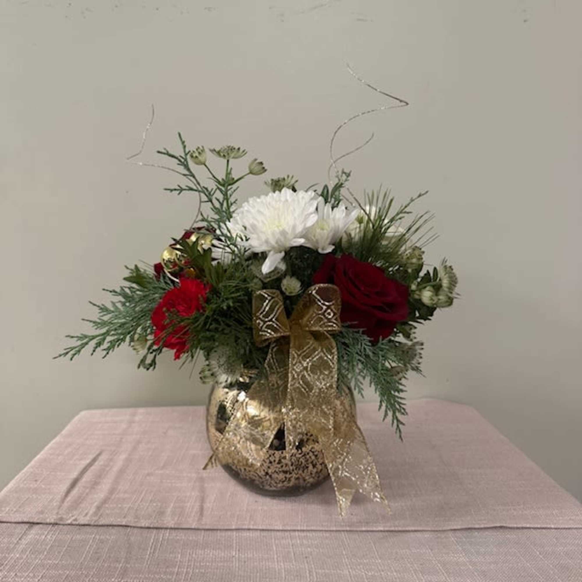 Red and white floral arrangement in a gold vase with a ribbon