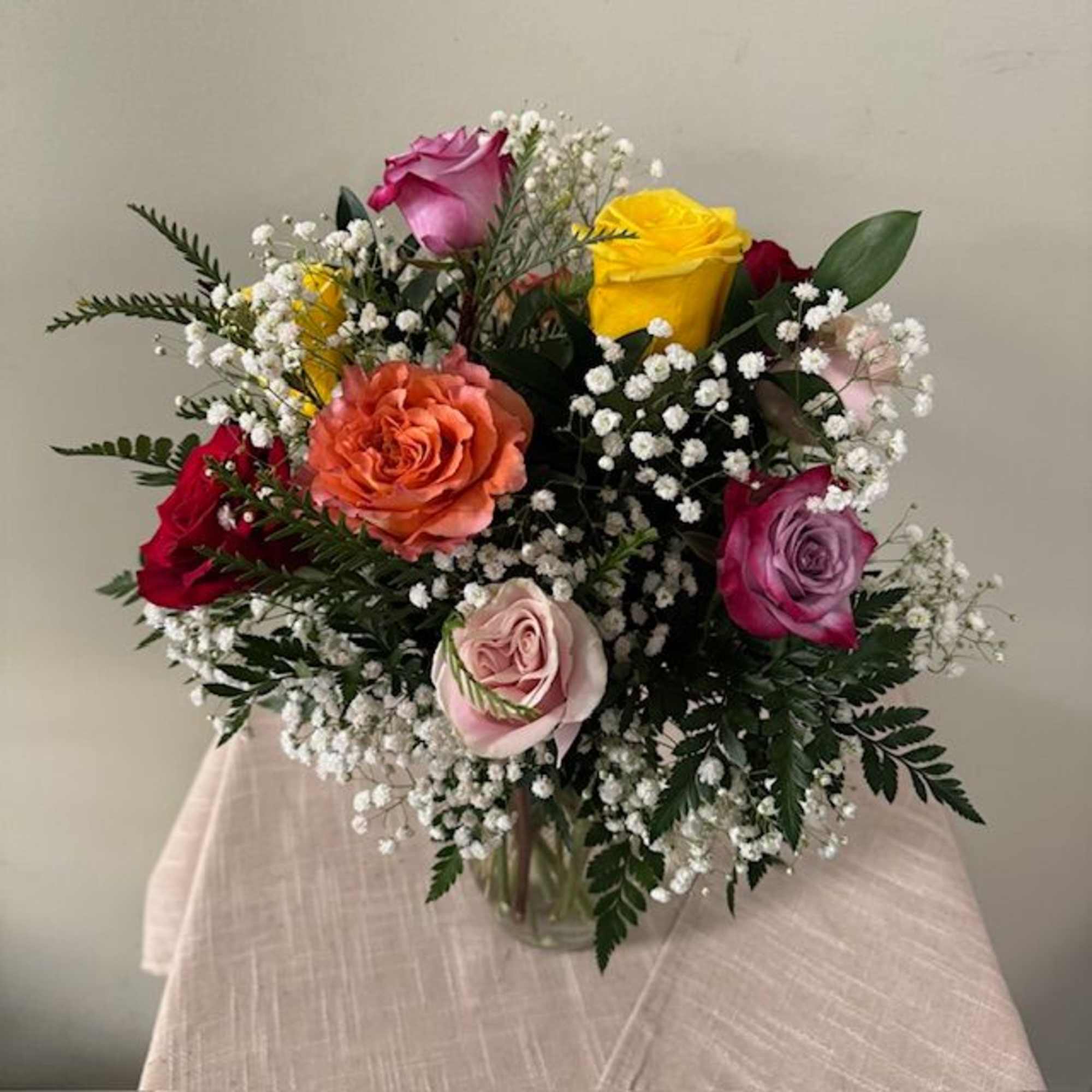 Mixed roses in a glass vase with baby's breath