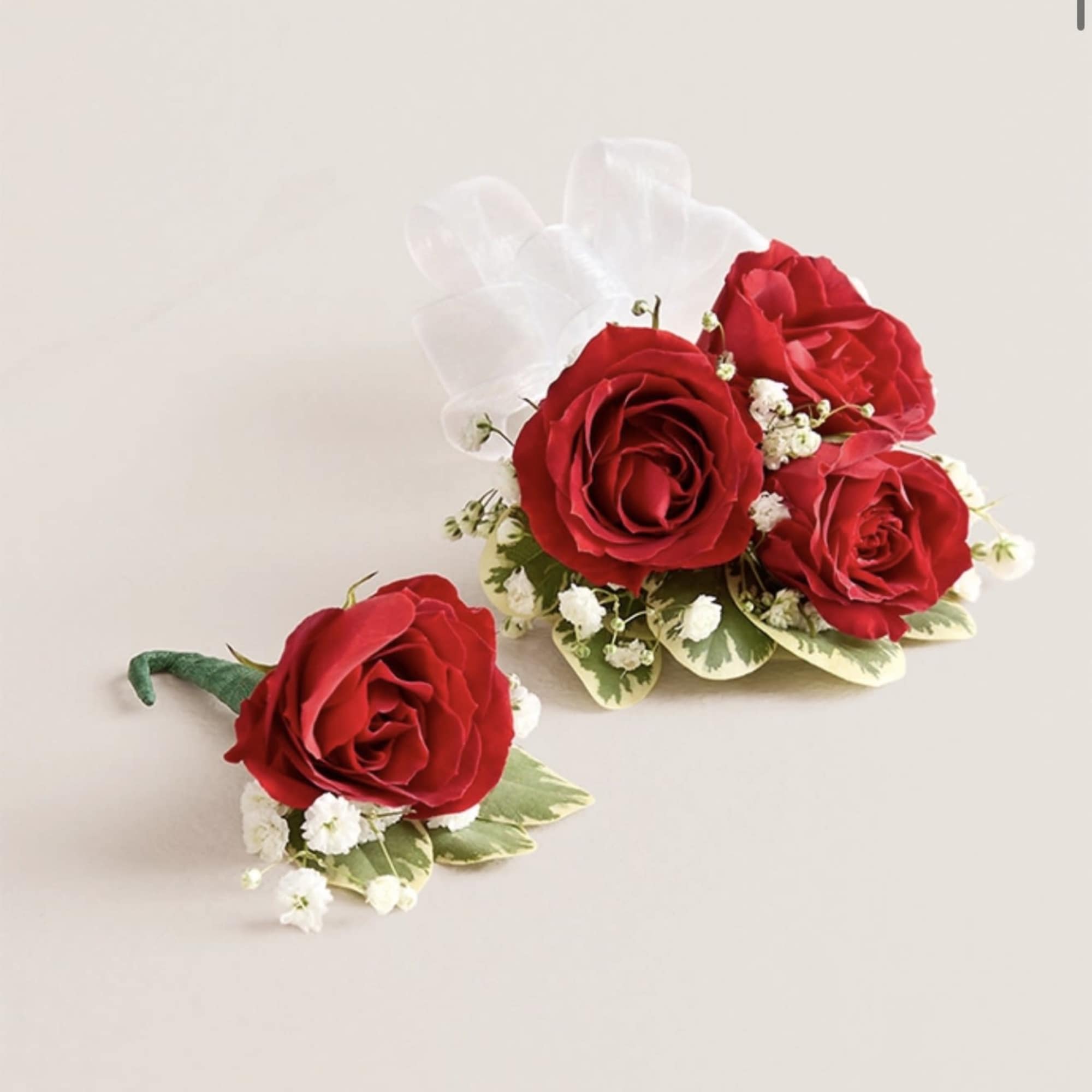 This elegant corsage and boutonniere set, featuring vibrant red blooms, is thoughtfully