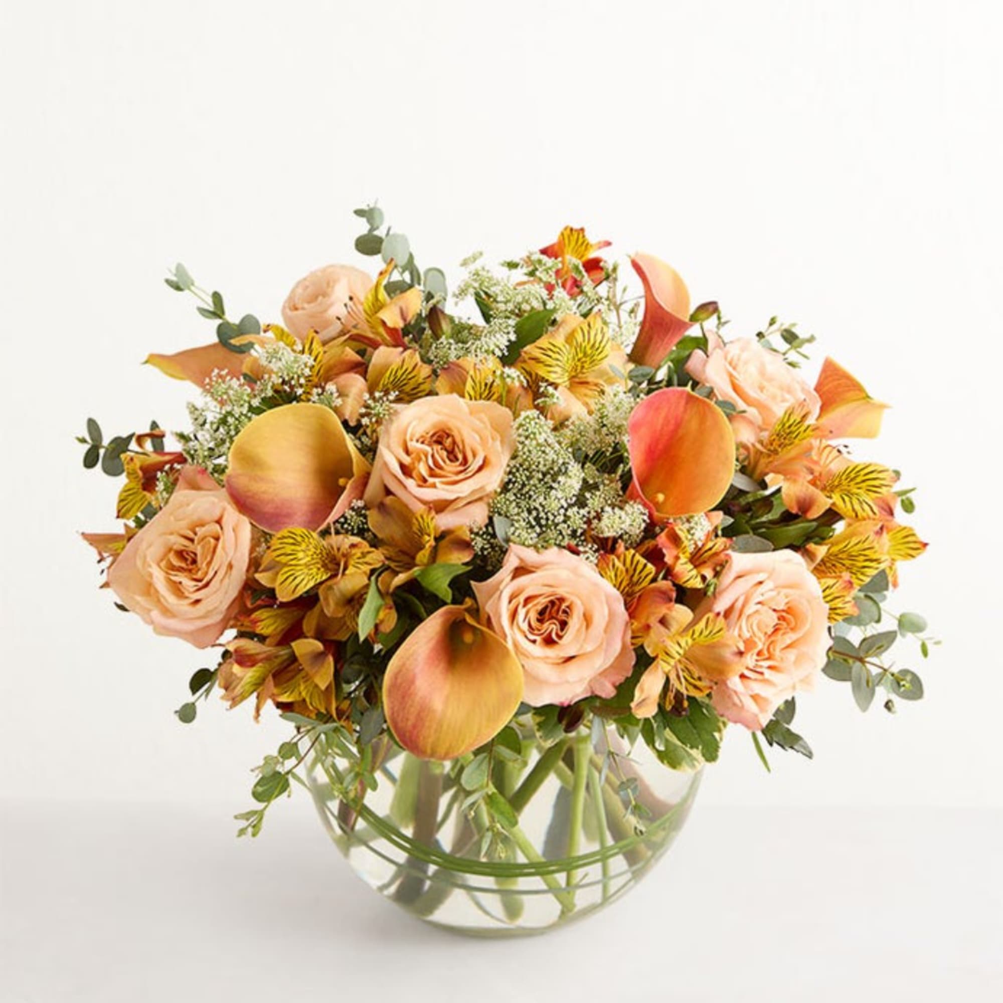 Peach roses and calla lilies in a clear glass vase