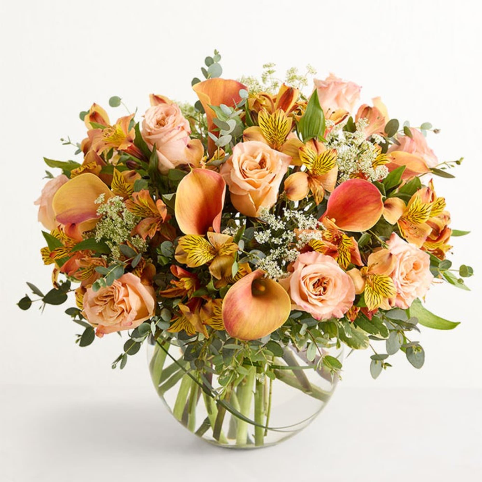 Peach roses and orange calla lilies in a clear glass vase