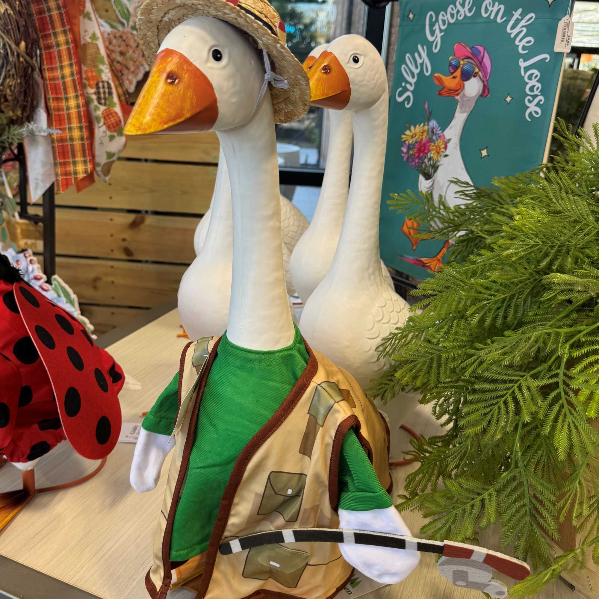 Decorative goose figurines in clothing, displayed with a ladybug decoration