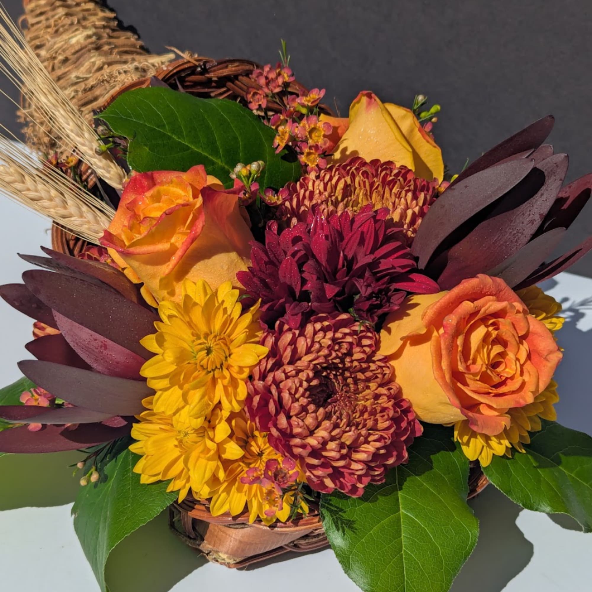 Autumn bouquet with orange roses and yellow chrysanthemums in a wicker basket